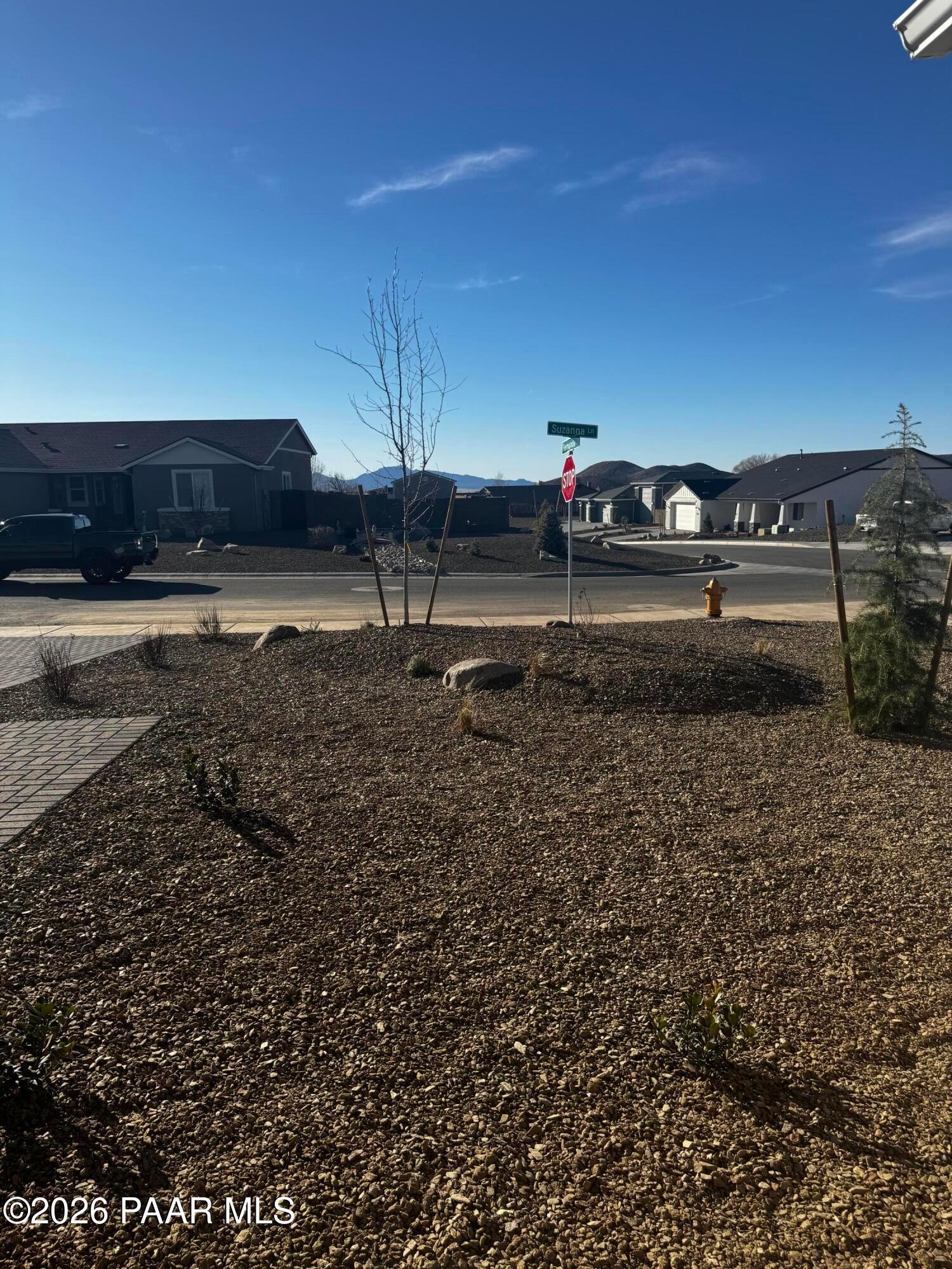 Street view of gravel landscaped lot with young trees and stop sign in Morningstar, Prescott Valley, Arizona 3-bedroom home community