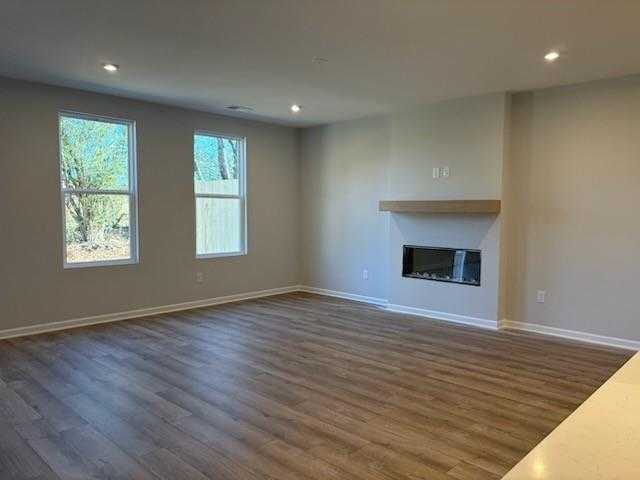 Spacious great room featuring modern linear gas fireplace, hardwood floors, and large windows in Davidson Homes Cary A, Winder, Georgia