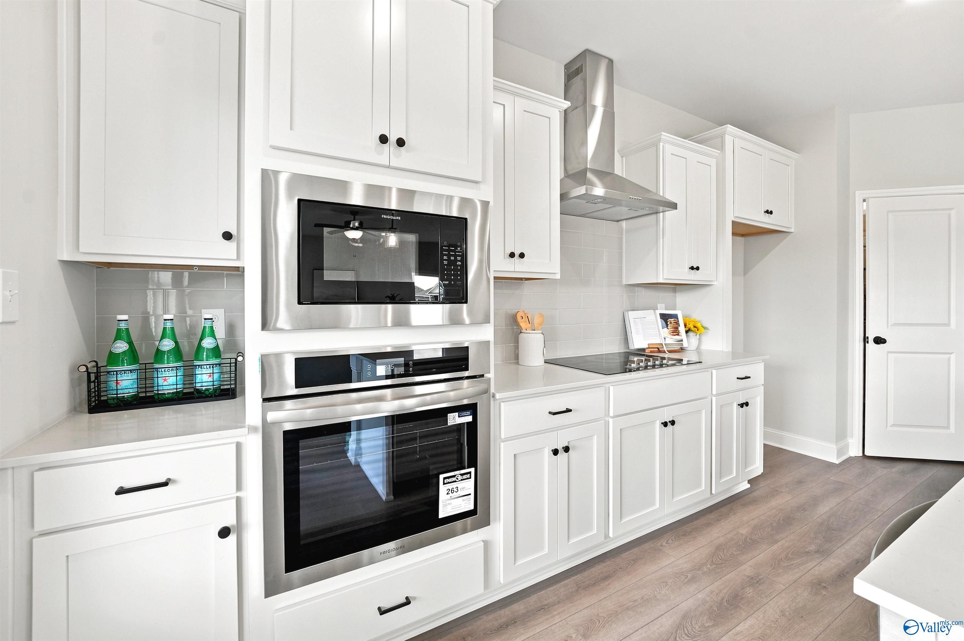 Modern kitchen with white cabinets, stainless steel appliances, and sleek range hood in The Burton B at Heritage Lakes.
