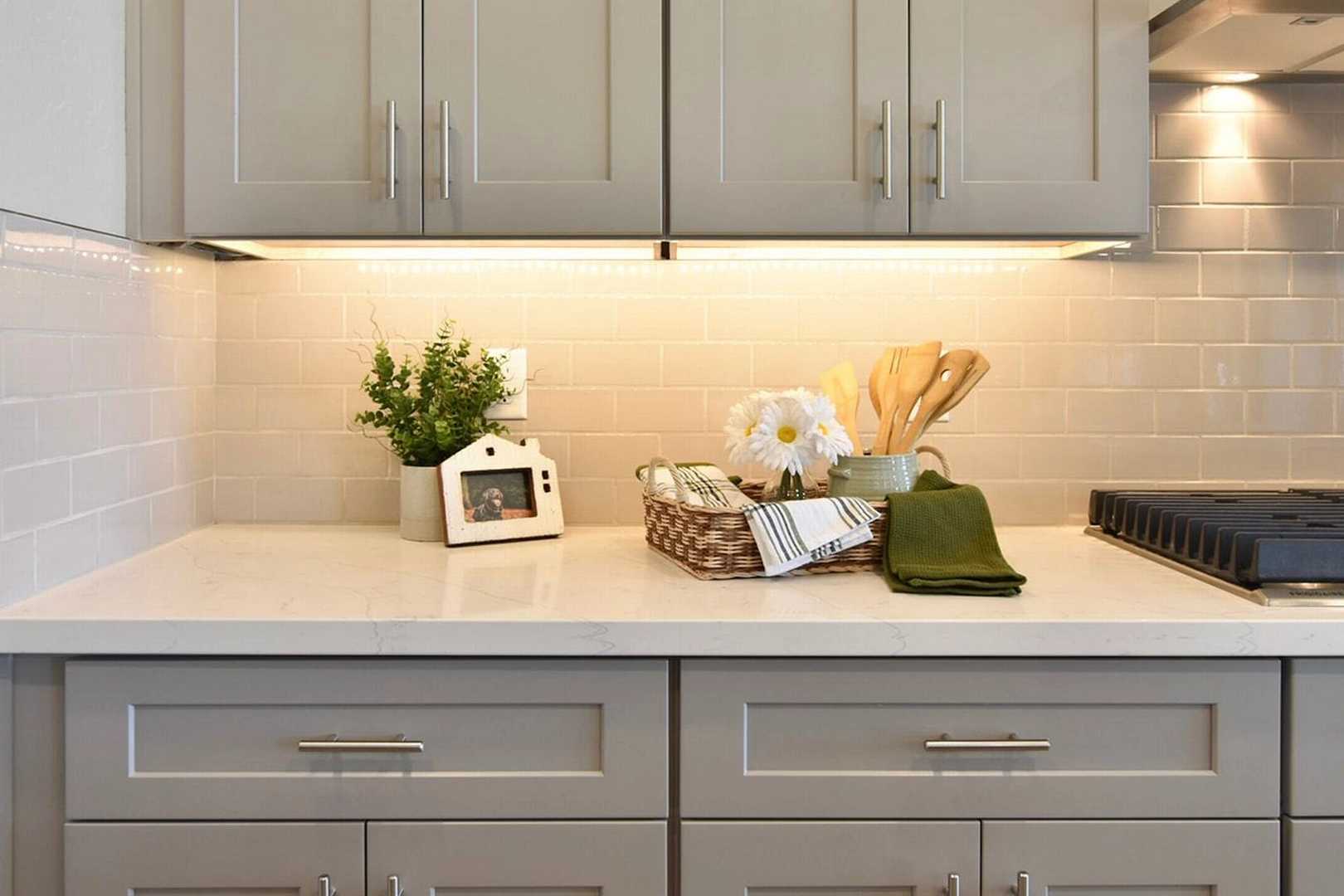 Modern kitchen with gray shaker cabinets, white subway tile backsplash, quartz counters, and decorative flowers at North Ridge Pronghorn Ranch in Prescott Valley AZ