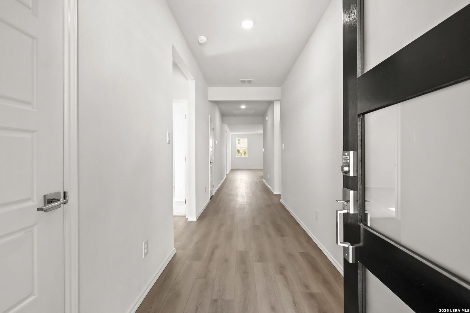 Bright entry hallway with luxury vinyl plank flooring and black glass-panel front door in Davidson Homes' The Daphne I, Bricewood, San Antonio