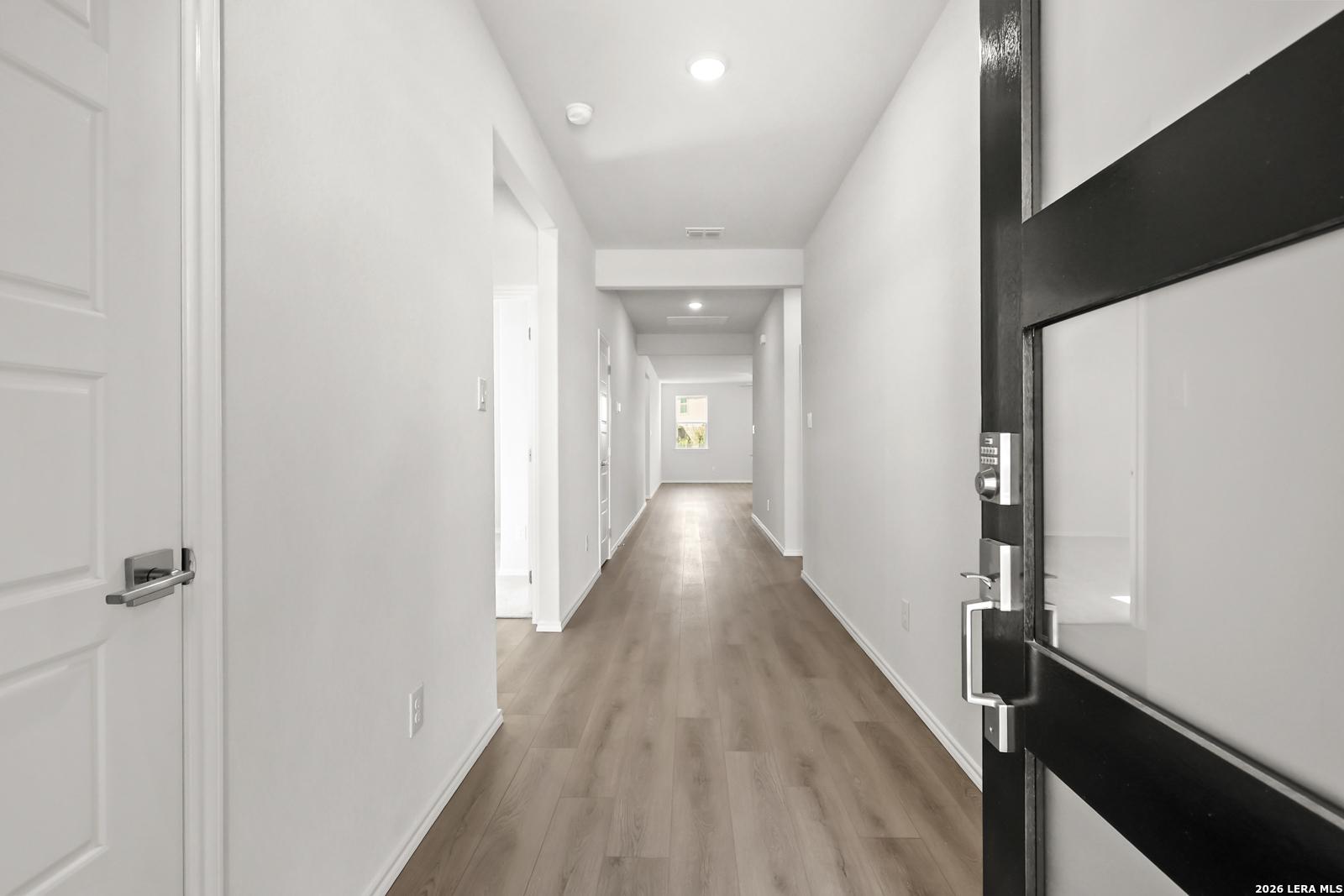 Bright entry hallway with luxury vinyl plank flooring and black glass-panel front door in Davidson Homes' The Daphne I, Bricewood, San Antonio