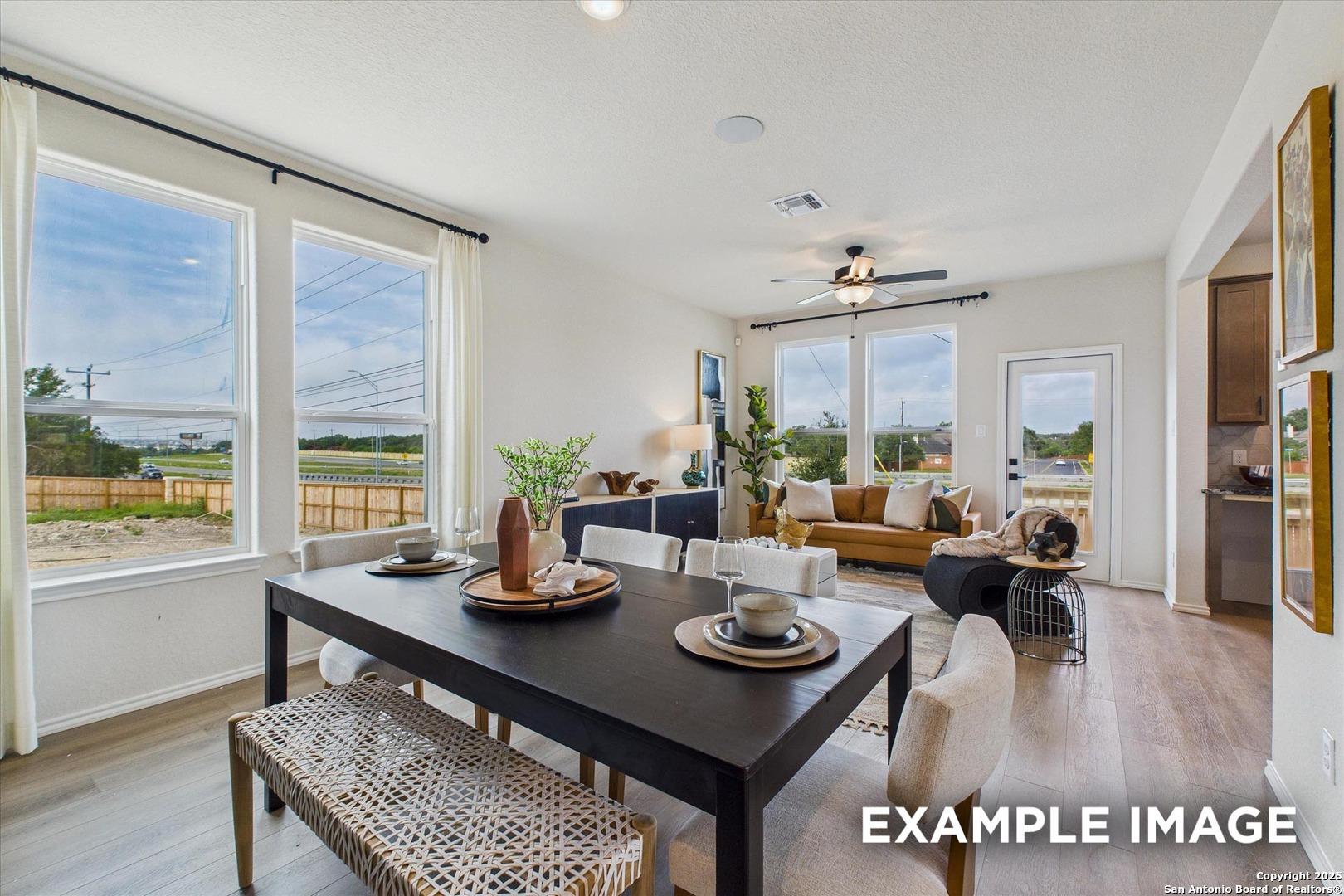 Bright open-concept dining and living room with large windows, modern table, and sofa in Davidson Homes The Florence C, San Antonio