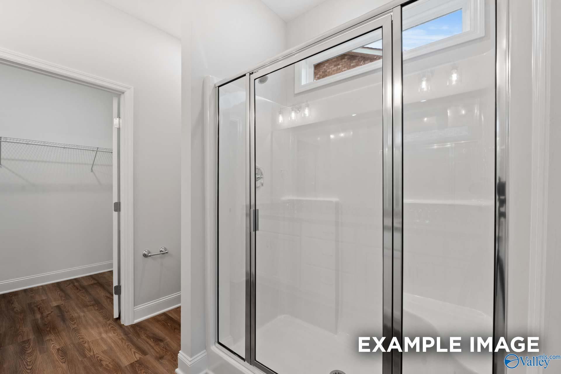 Modern master bathroom with frameless glass shower, transom window, and walk-in closet in Davidson Homes The Cumberland, Decatur, Alabama