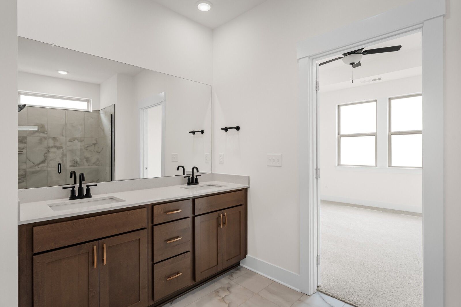 Modern primary bathroom with double vanity and tiled walk-in shower in The Prairie C floor plan, Woods Crossing, Gallatin.