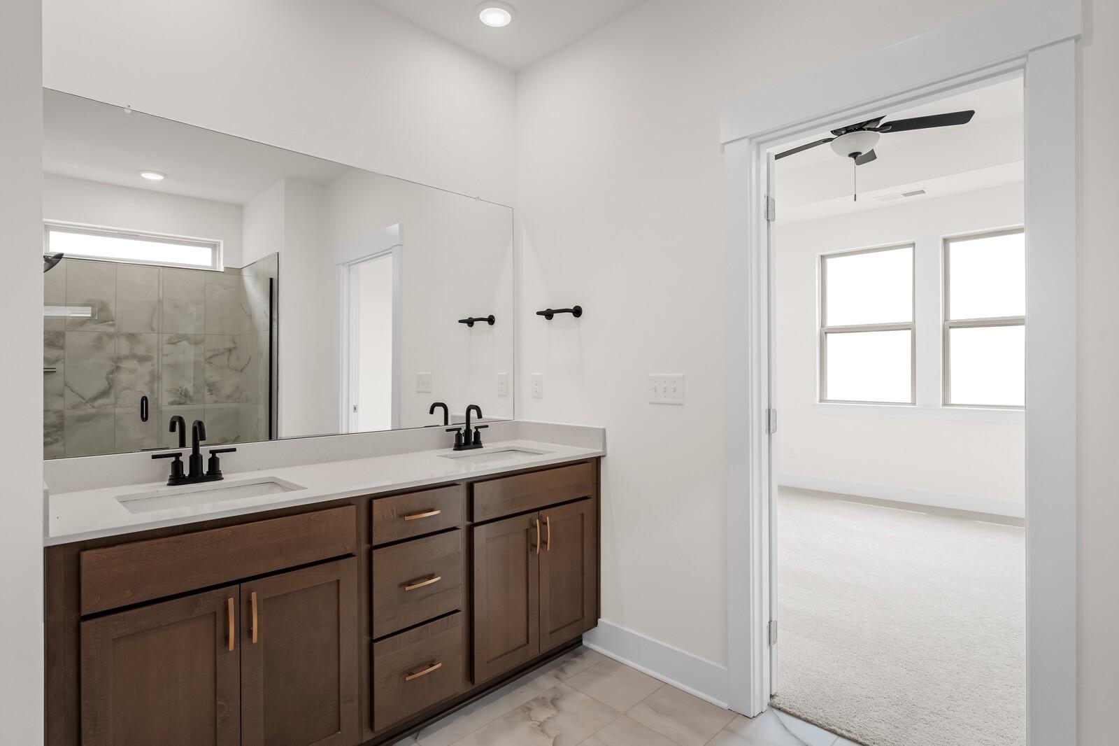 Modern primary bathroom with double vanity and tiled walk-in shower in The Prairie C floor plan, Woods Crossing, Gallatin.