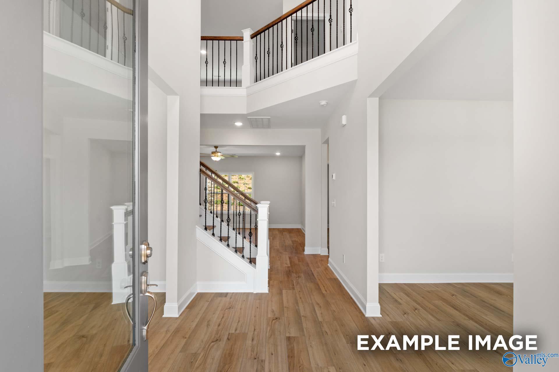 Grand foyer featuring wooden staircase with wrought iron balusters and hardwood floors in Davidson Homes The Madison A, Meridianville, Alabama