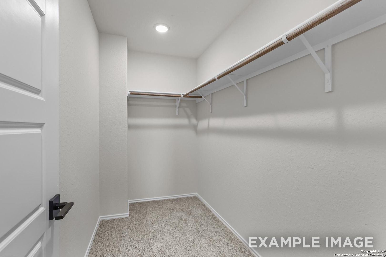 Spacious walk-in closet with neutral walls, carpet floor, built-in shelves in Davidson Homes The Trinity B, San Antonio