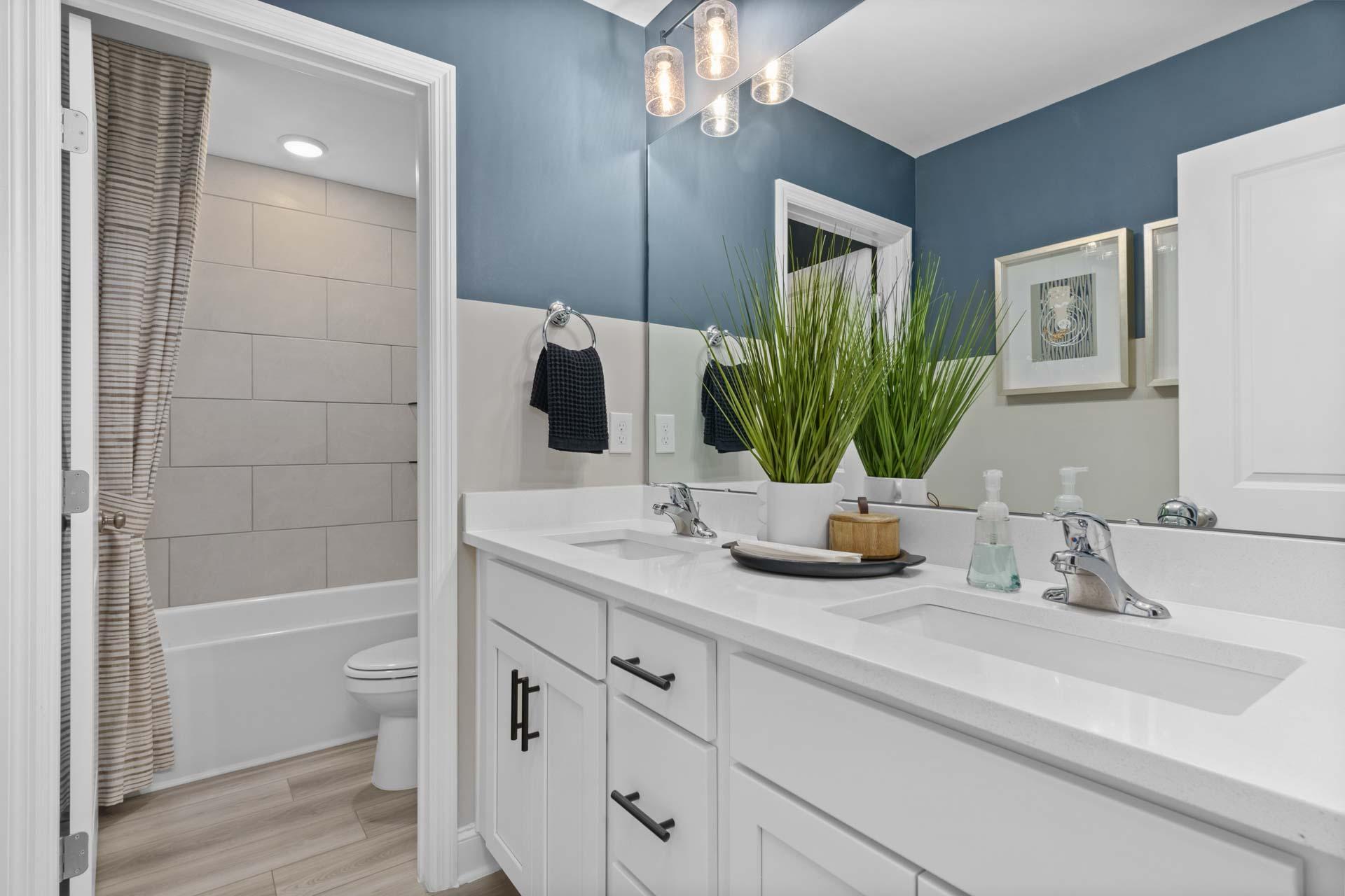 Spacious bathroom at Creek Grove in New Market Alabama with navy walls dual vanities subway tile shower and hardwood floors