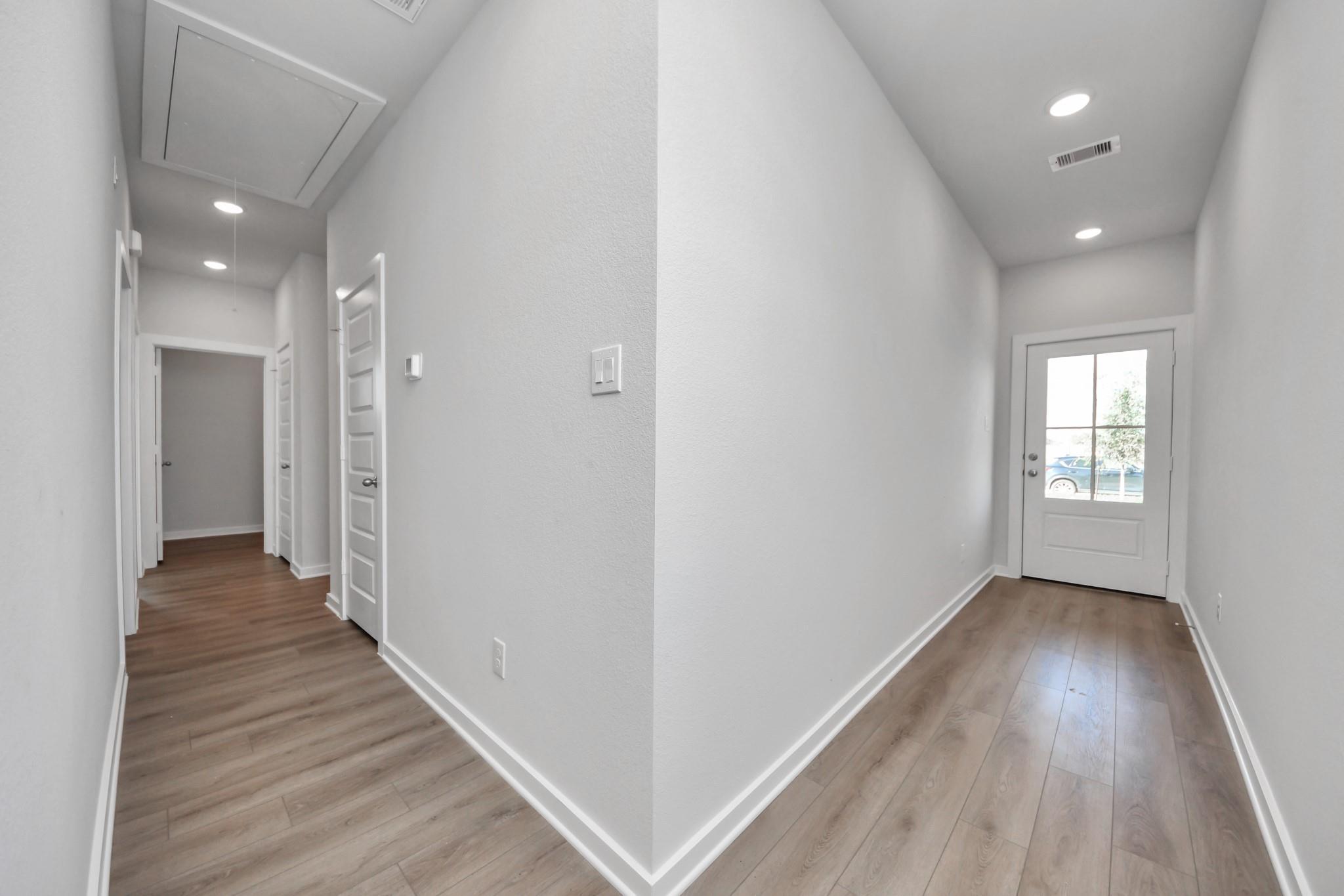 Bright entryway with wood-style flooring and glass-paneled front door in The Colorado G home by Davidson Homes in Emberly.