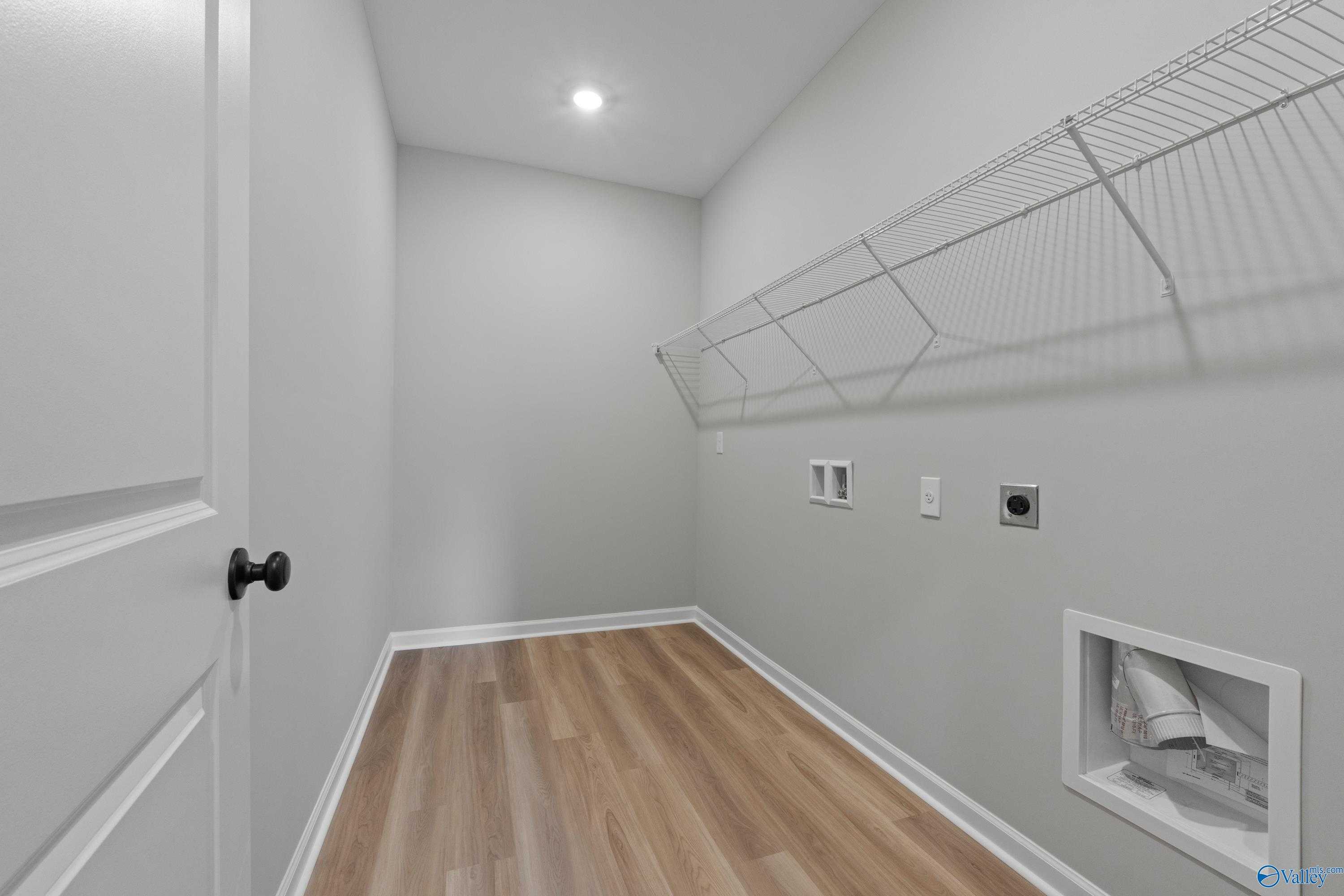 Modern laundry room with wire shelving, outlets, dryer vent, and luxury vinyl plank flooring in Davidson Homes The Dorado, Huntsville, AL