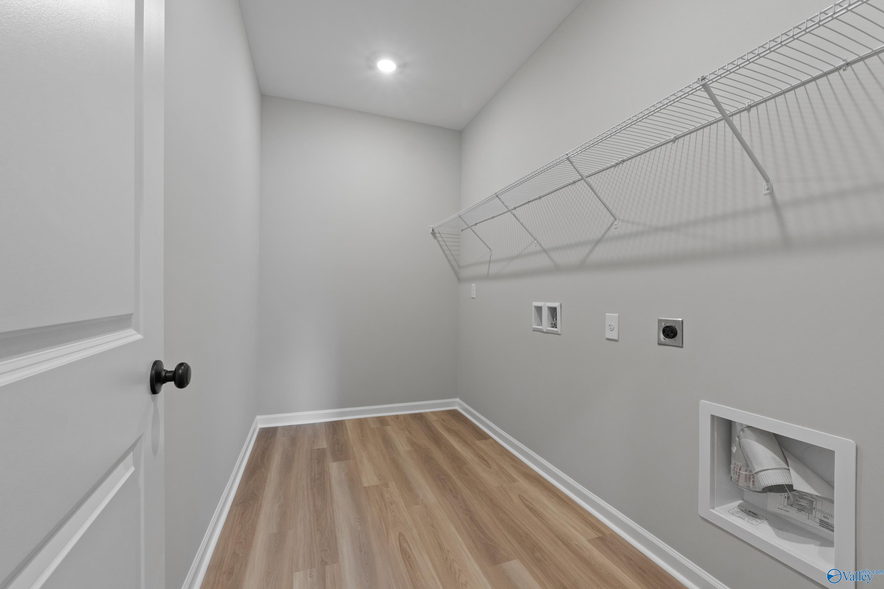 Modern laundry room with wire shelving, outlets, dryer vent, and luxury vinyl plank flooring in Davidson Homes The Dorado, Huntsville, AL