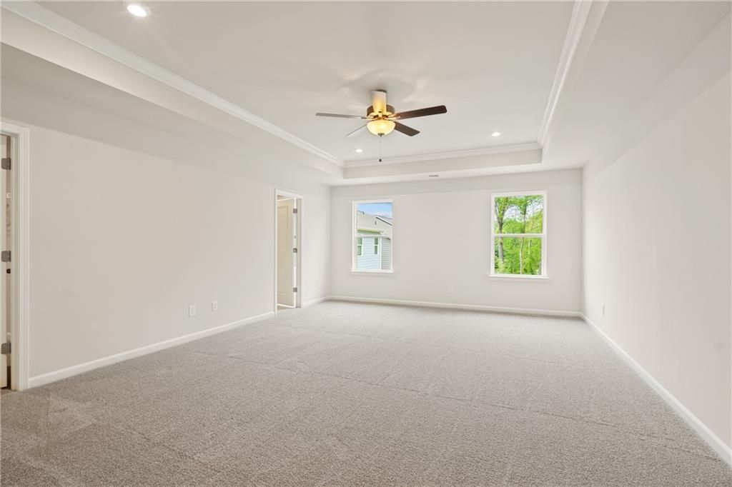 Spacious empty bedroom with ceiling fan, large windows, and neutral carpet in Davidson Homes The Cary B, Kennesaw, GA
