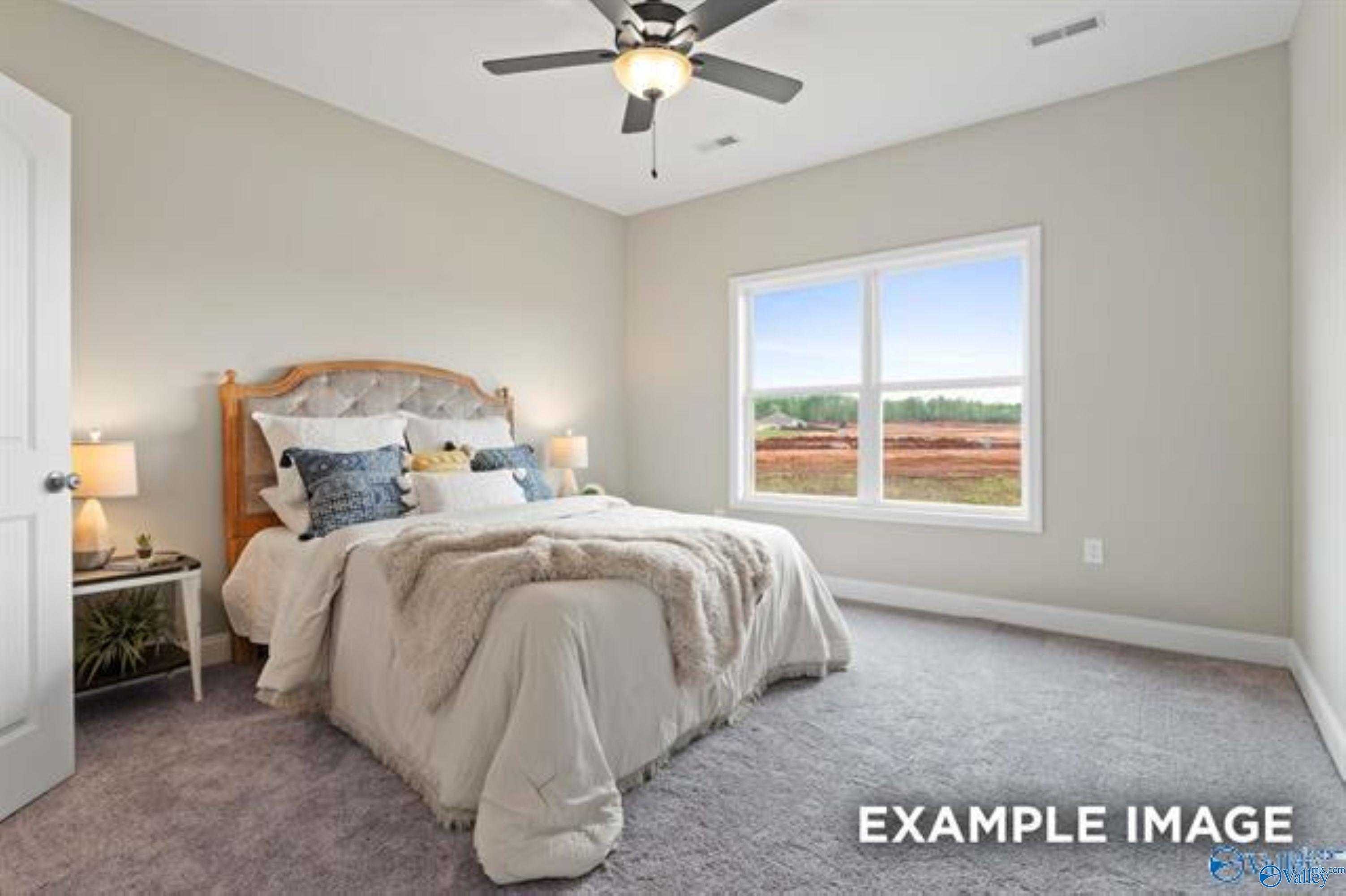 Cozy master bedroom with plush white bedding, wooden headboard, and scenic window view in Davidson Homes The Asheville, Owens Cross Roads, AL