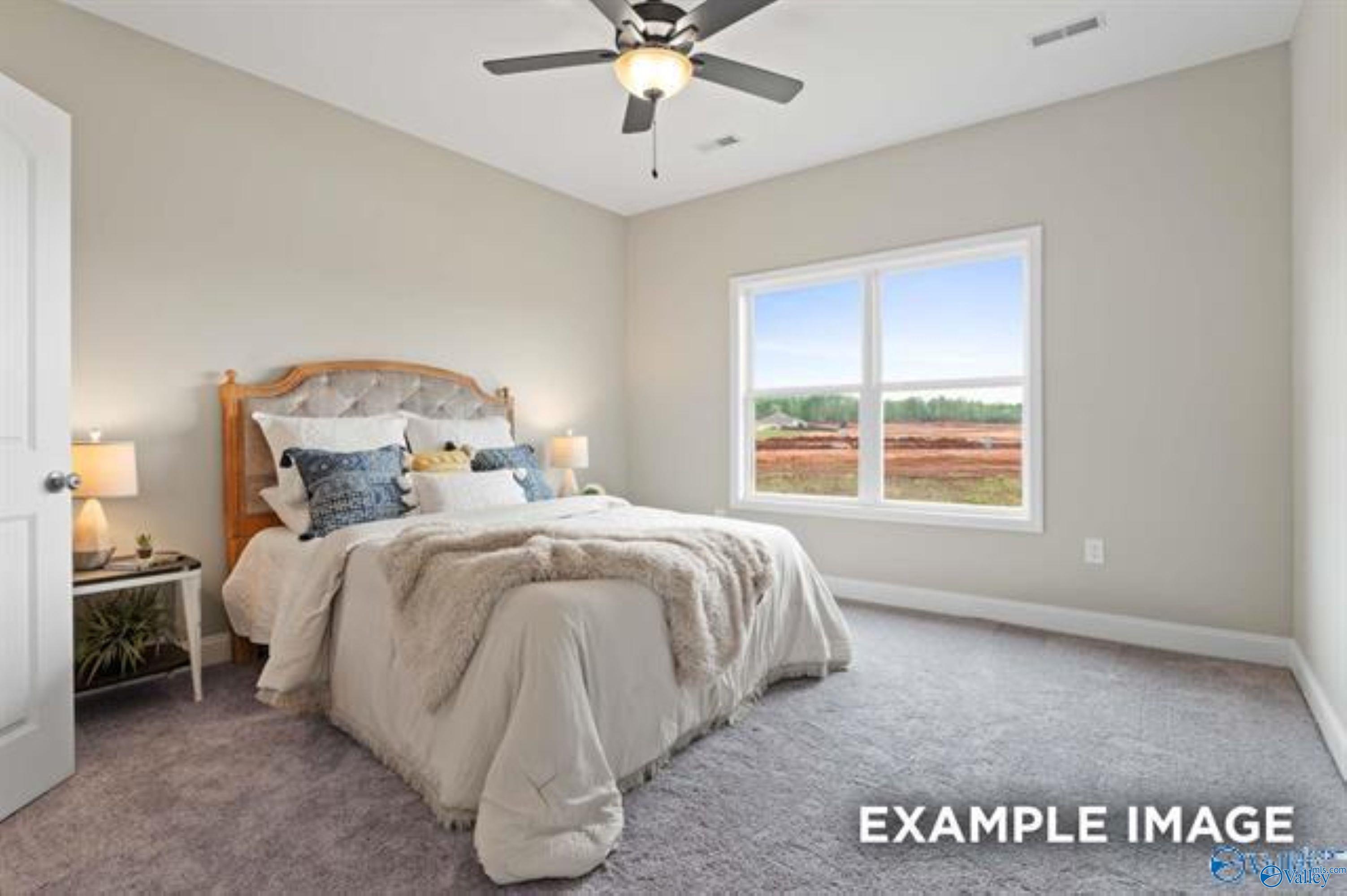 Bright bedroom with plush carpet and ceiling fan in The Asheville floor plan at Ramsay Cove, Owens Cross Roads, Alabama.