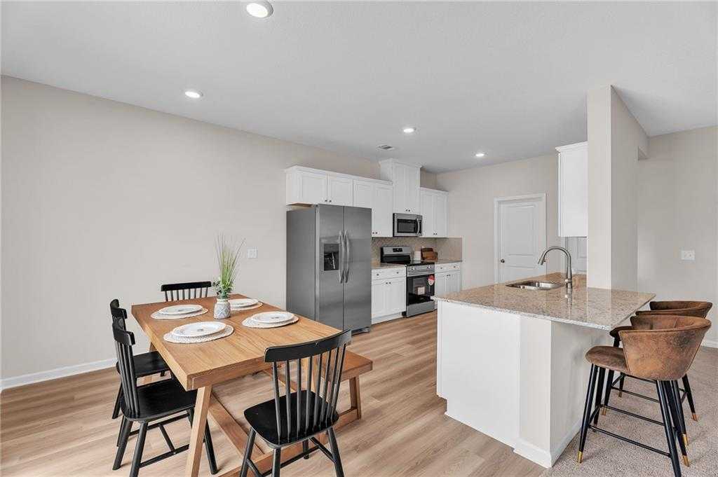 Modern open-concept kitchen dining area with granite island, stainless appliances, wooden table in Davidson Homes The Bartlett, Phenix City, Alabama