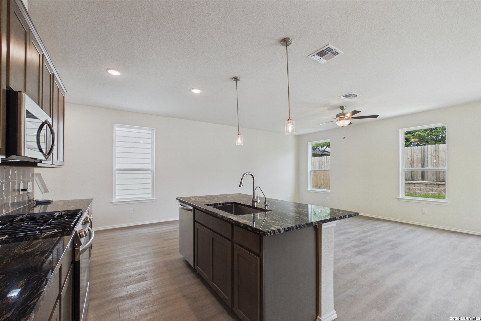 Open-concept kitchen with granite island in The Charlotte B floor plan at Meadows at Oak Creek, San Antonio, Texas.