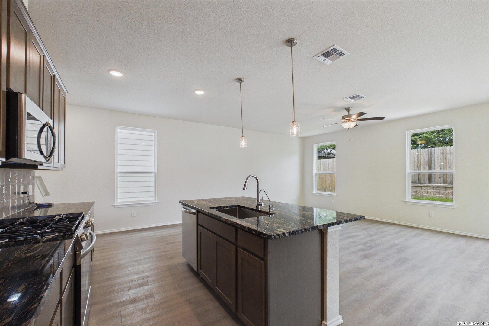 Open-concept kitchen with granite island in The Charlotte B floor plan at Meadows at Oak Creek, San Antonio, Texas.
