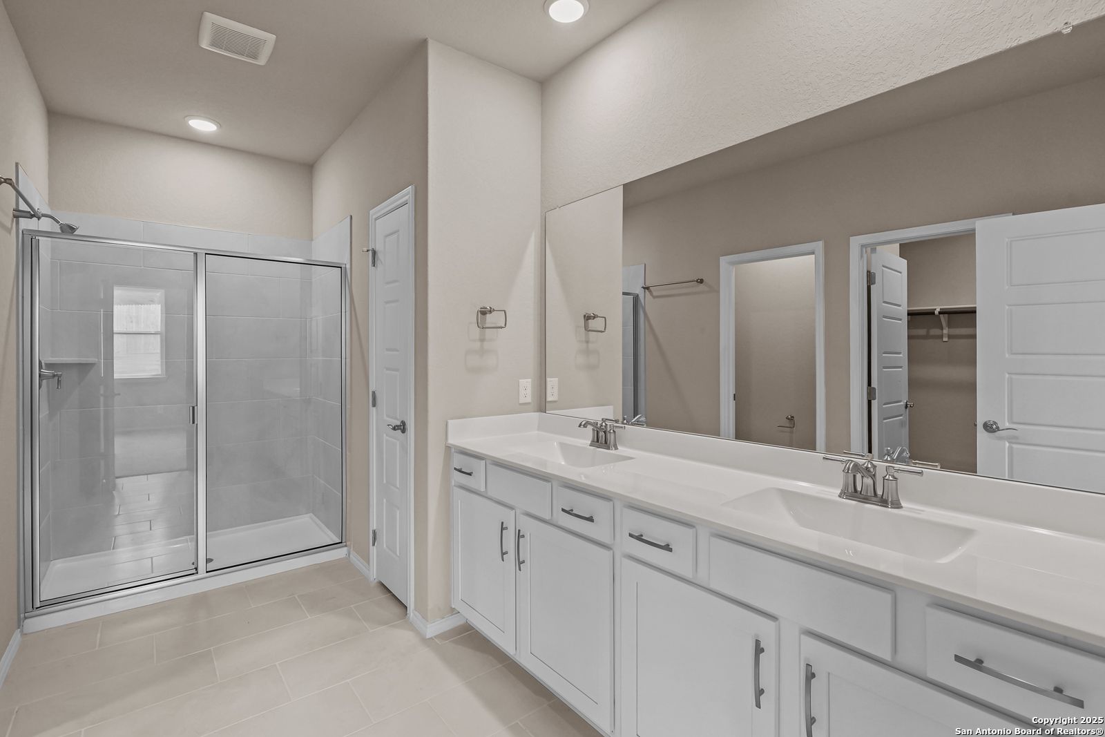 Modern master bathroom with double vanity, frameless glass shower, and linen closet in Davidson Homes The Douglas G, San Antonio, Texas
