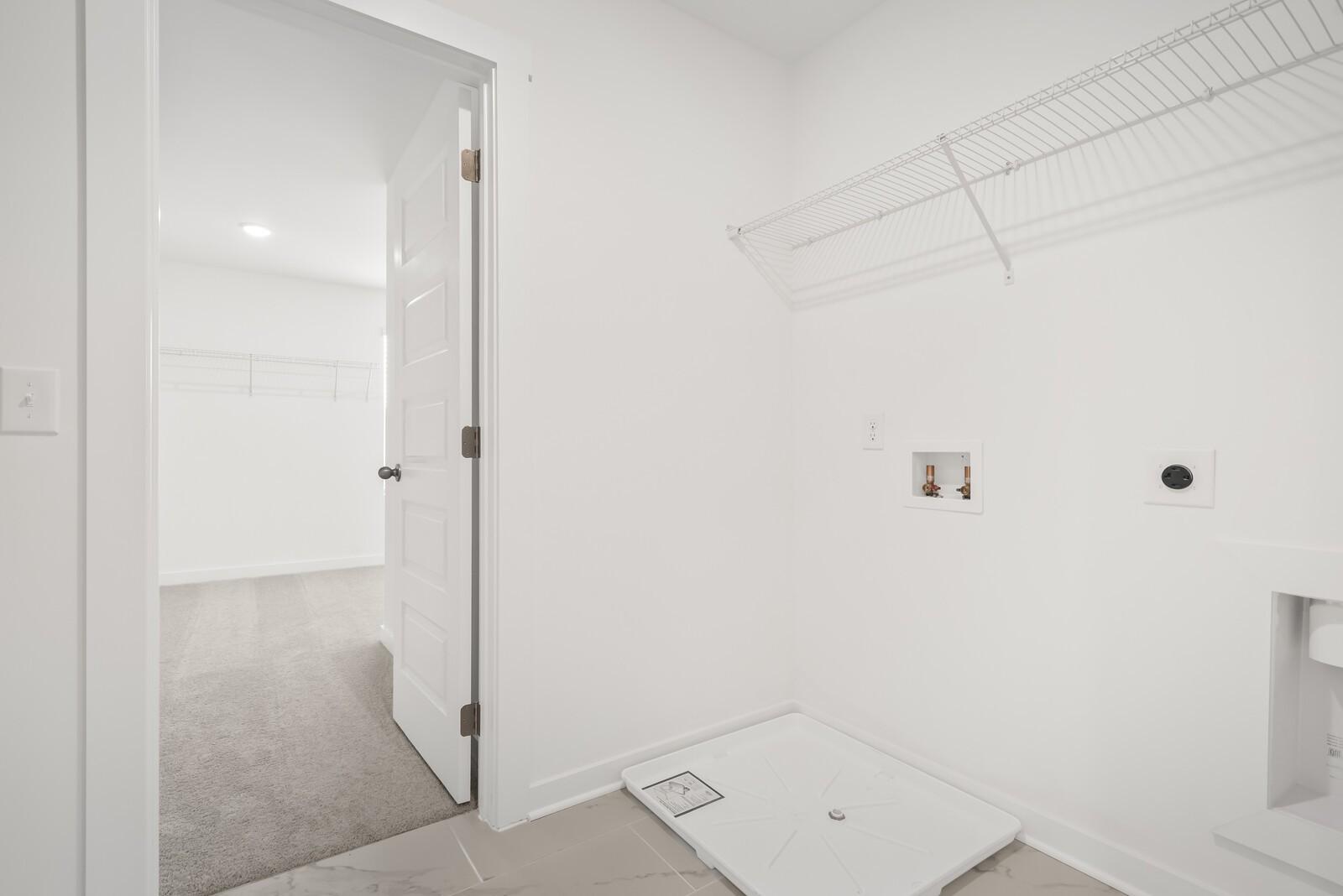 Bright laundry room with wire shelving, utility sink, and washer dryer hookups in Davidson Homes The Gordon C, Sage Farms, White House, Tennessee