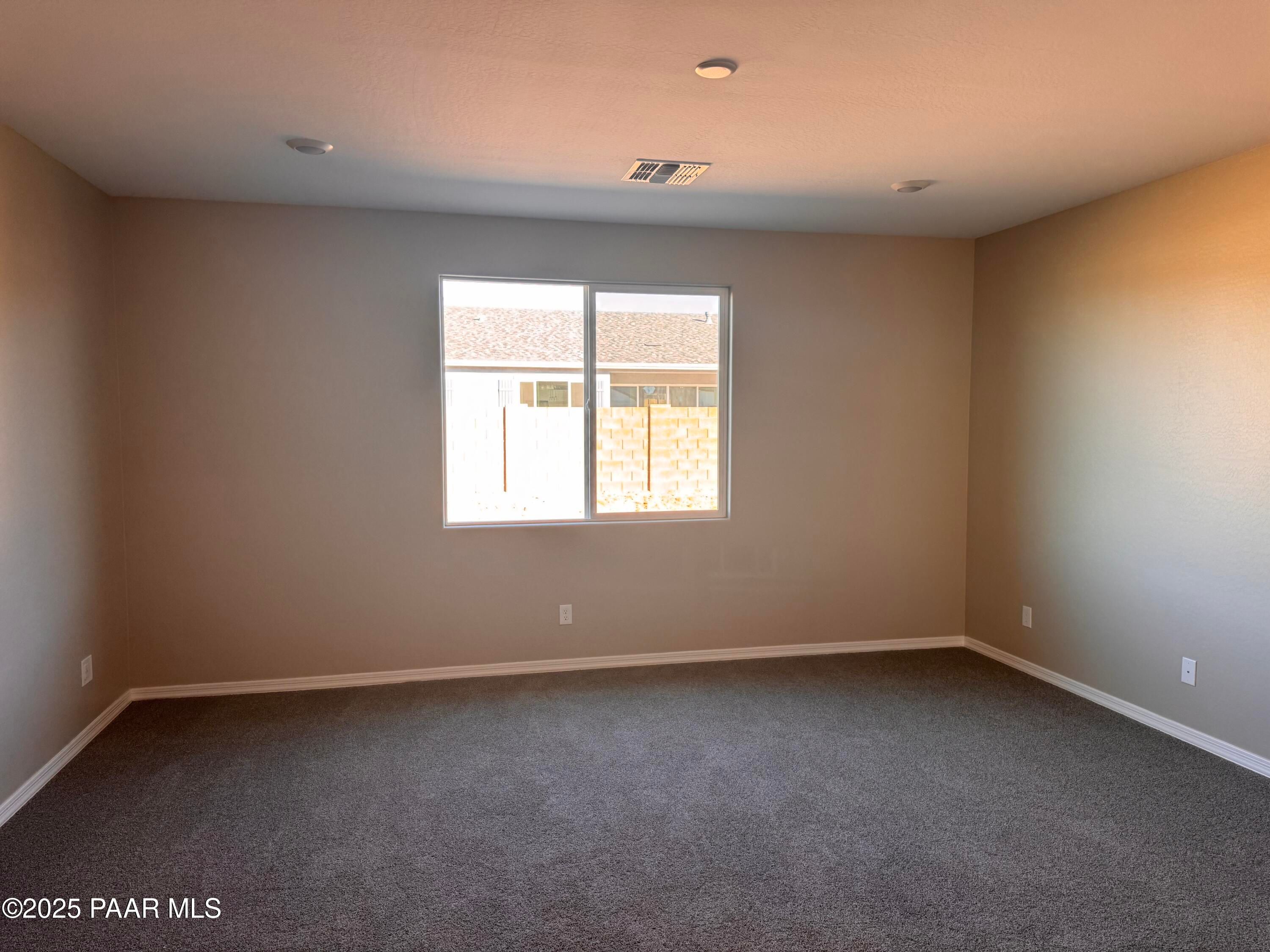 Empty bedroom featuring beige walls, gray carpet, and large window overlooking backyard in Davidson Homes The Sunrise II A, Prescott, Arizona