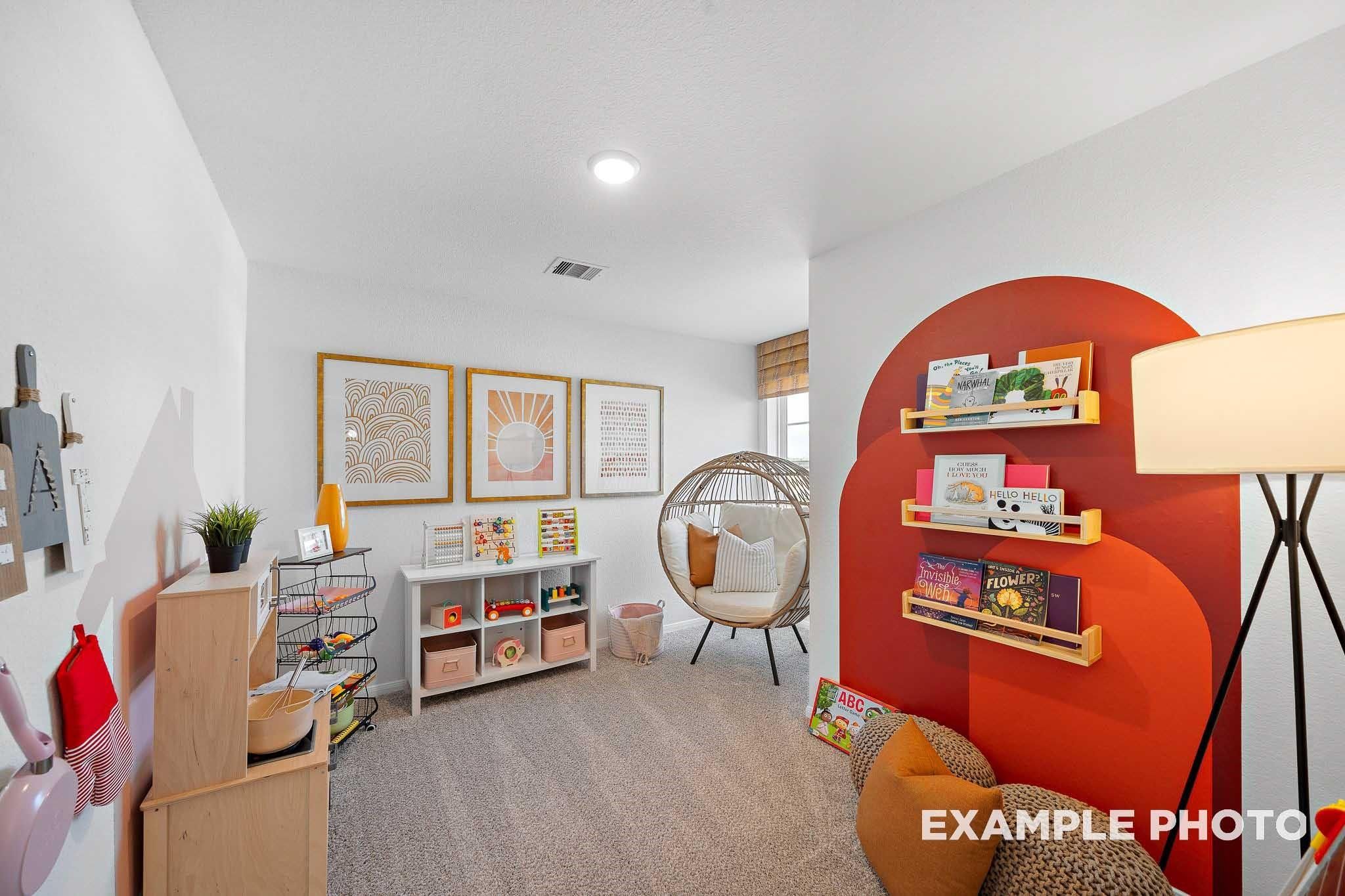 Cozy children's playroom with orange bookshelves, toy kitchen, and hanging egg chair in Davidson Homes The Sabine F, Magnolia, Texas