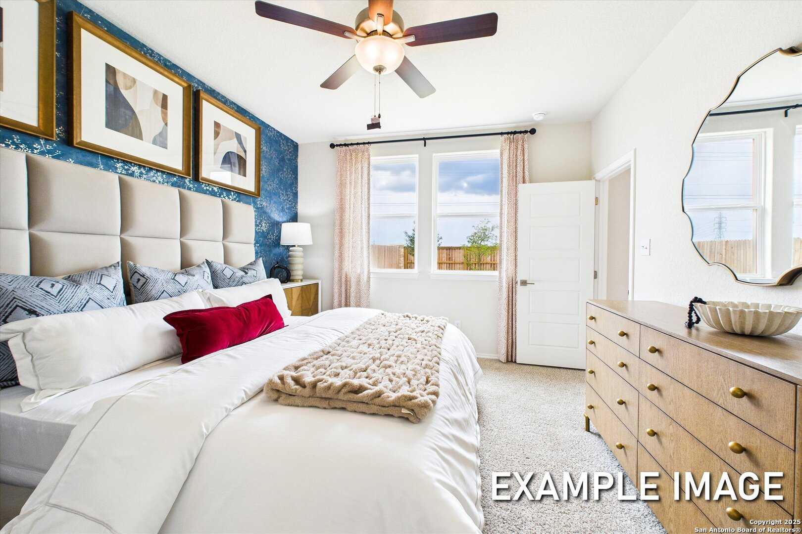 Elegant master bedroom with white bedding, wooden dresser, ceiling fan, and large windows in Davidson Homes The Brazos C, San Antonio