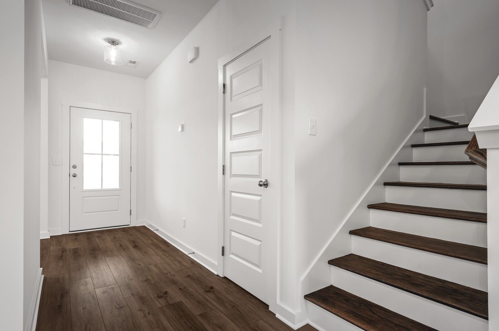 Bright foyer with hardwood floors, white doors, and staircase in The Willow floor plan at Calista Farms, White House, TN.