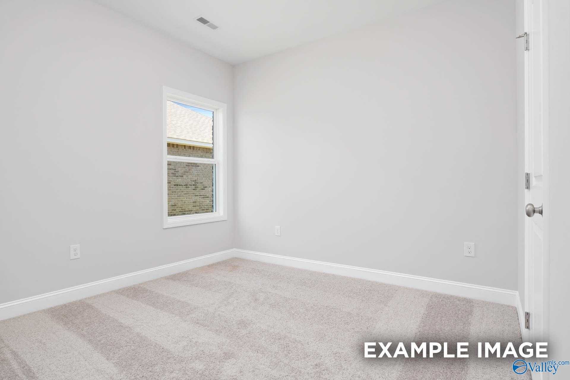 Bright secondary bedroom with light gray walls, beige carpet, and large window in Davidson Homes The Franklin C, Meridianville, Alabama