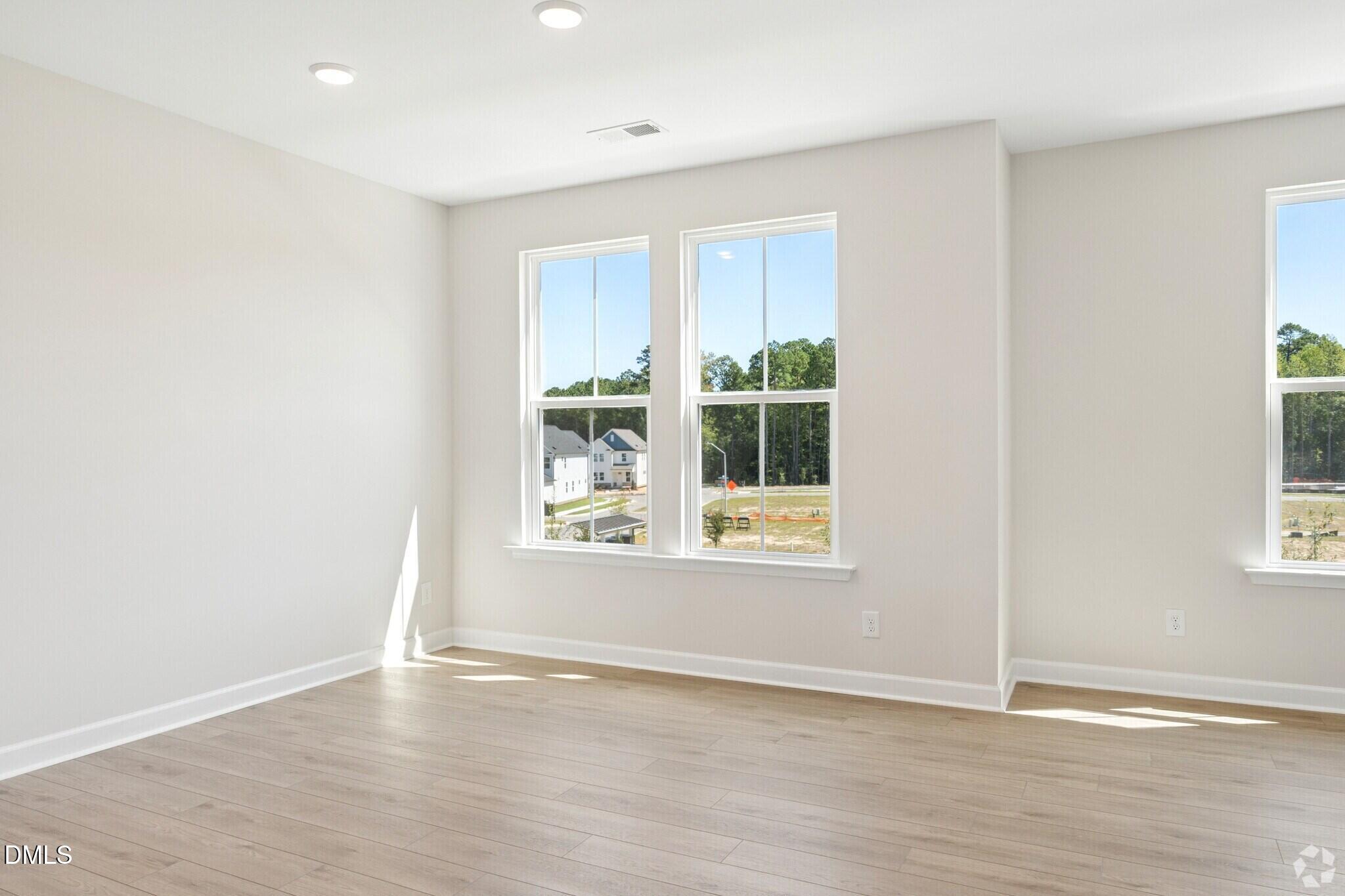 Bright empty bedroom with luxury vinyl plank flooring and double-hung windows in Davidson Homes The Mitchell plan, Knightdale, NC