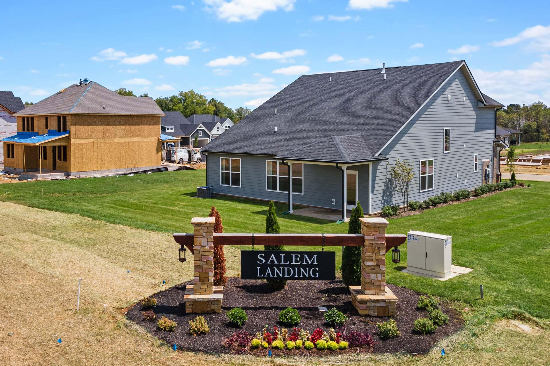 Salem Landing community sign with stone pillars and colorful flowers in Murfreesboro TN amid new home construction