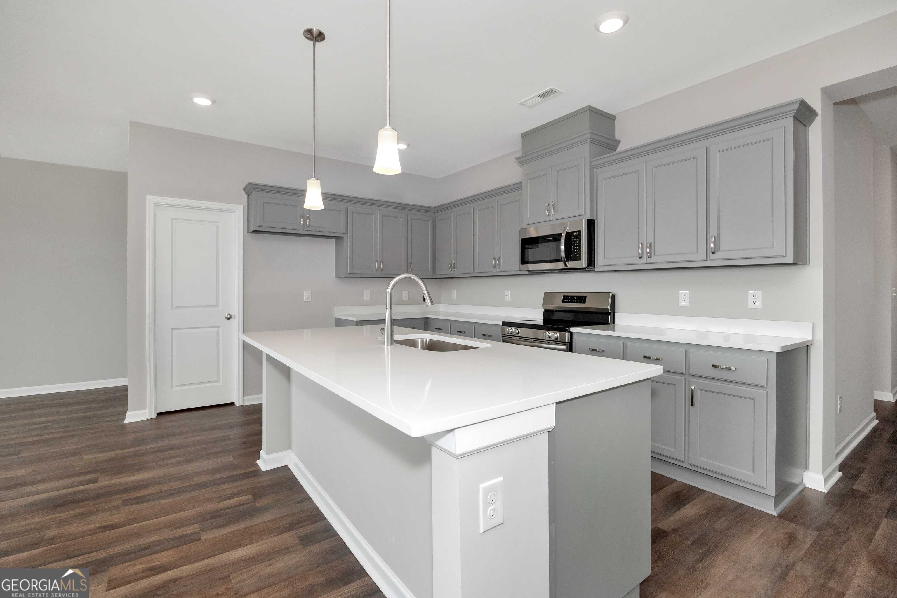 Modern kitchen featuring gray cabinets, white quartz island, stainless appliances in The Luna floor plan, Evermore Homes, Perry, GA