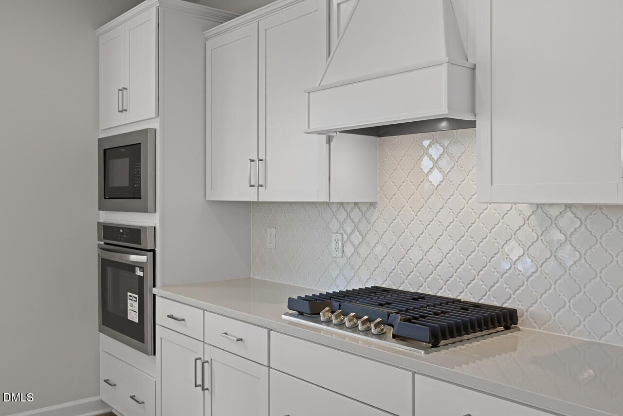 Modern kitchen with white cabinets, gas cooktop, and tile backsplash in The Chestnut floor plan at Wendell Ridge.