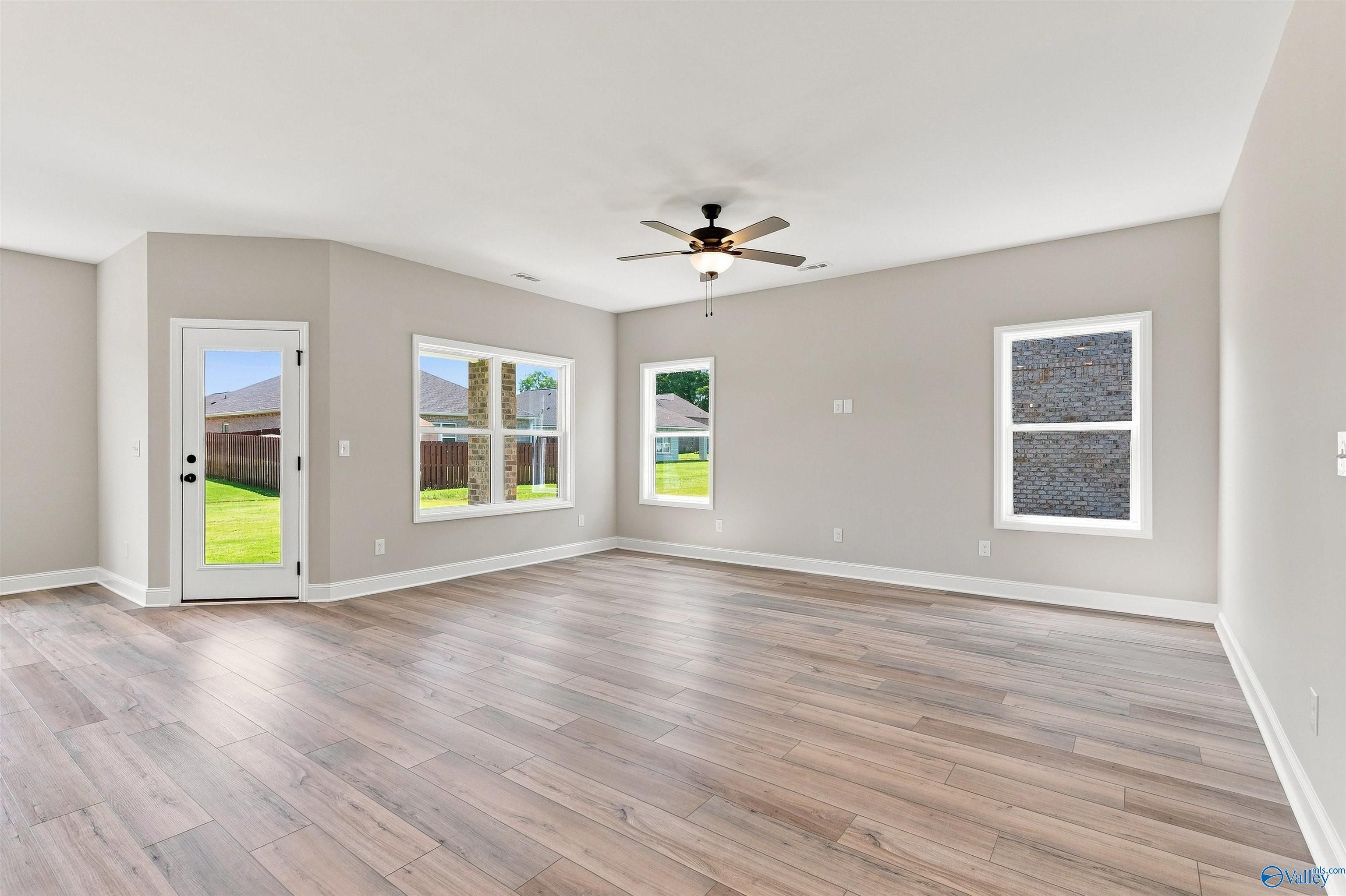 Bright open-concept living room with luxury vinyl plank flooring and ceiling fan in Davidson Homes Franklin C, Toney, Alabama