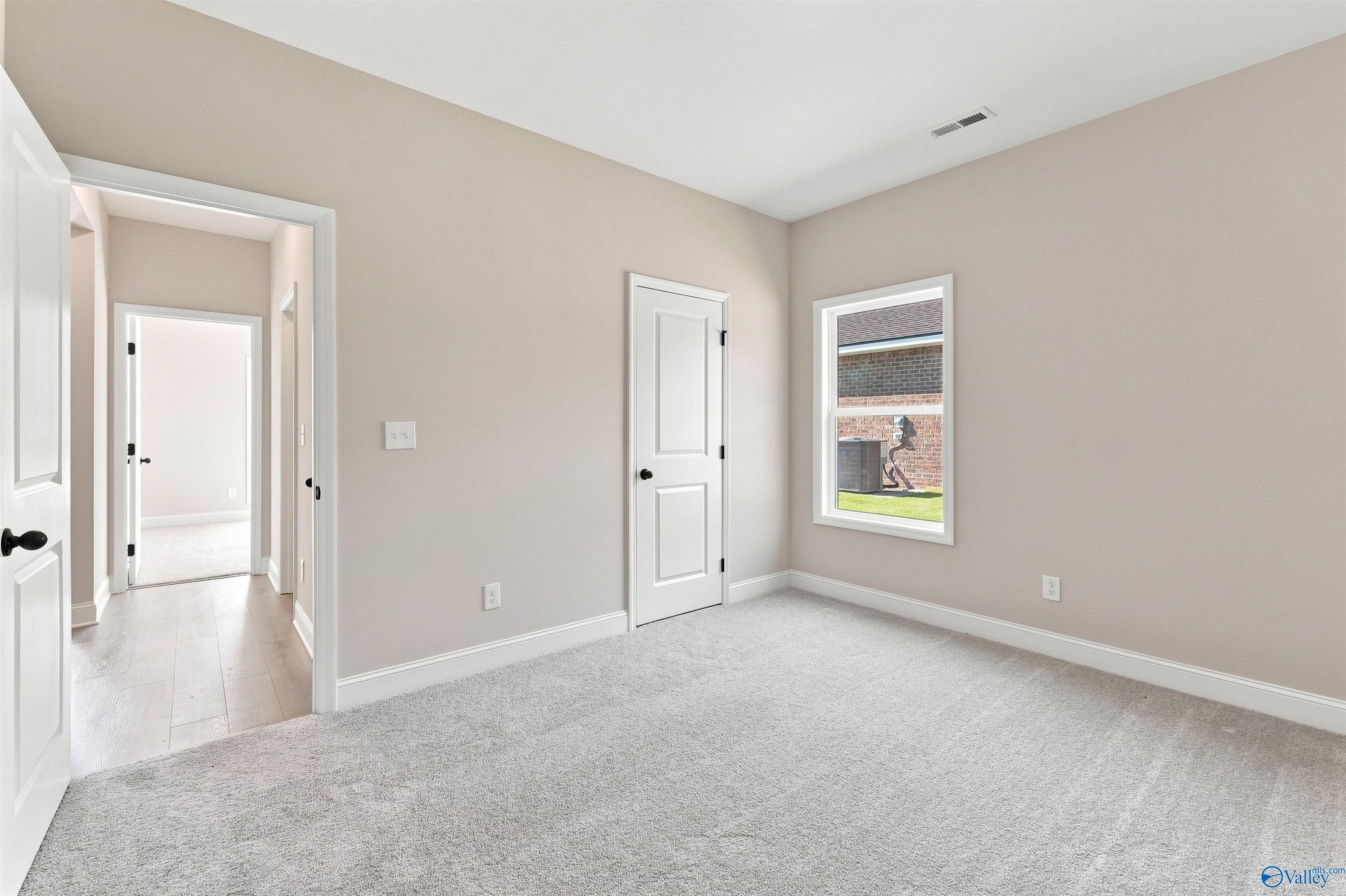 Bright, carpeted bedroom with neutral walls in The Daphne floor plan by Davidson Homes in Spragins Cove, Huntsville, AL.