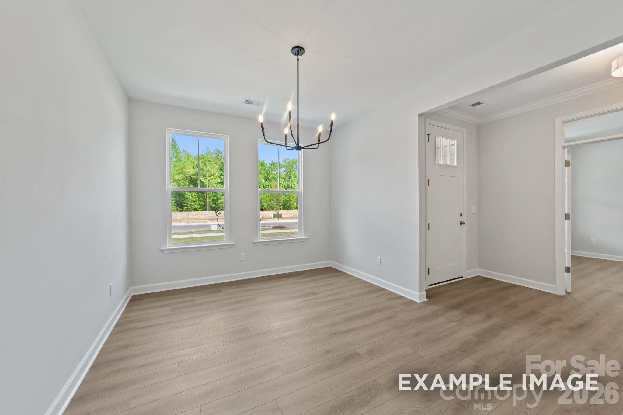 Bright dining area with modern chandelier and wood-style flooring in The Magnolia B floor plan, Windgate, Mooresville, NC.