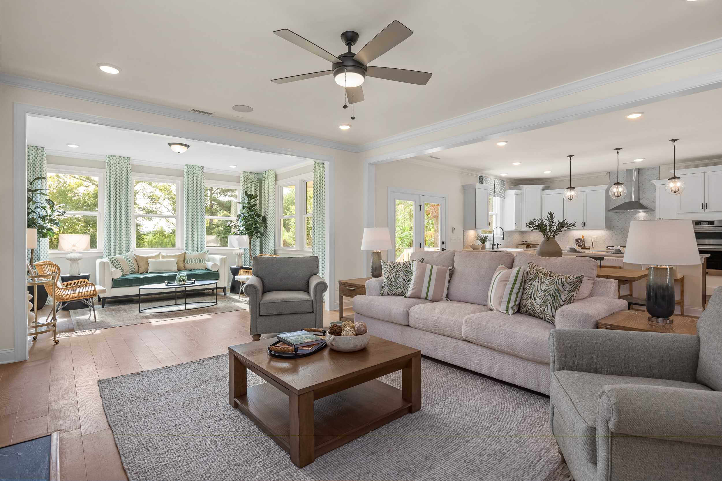 Open-concept living room and kitchen at Laneridge Estates in Raleigh NC with hardwood floors, sectional sofa, and large windows