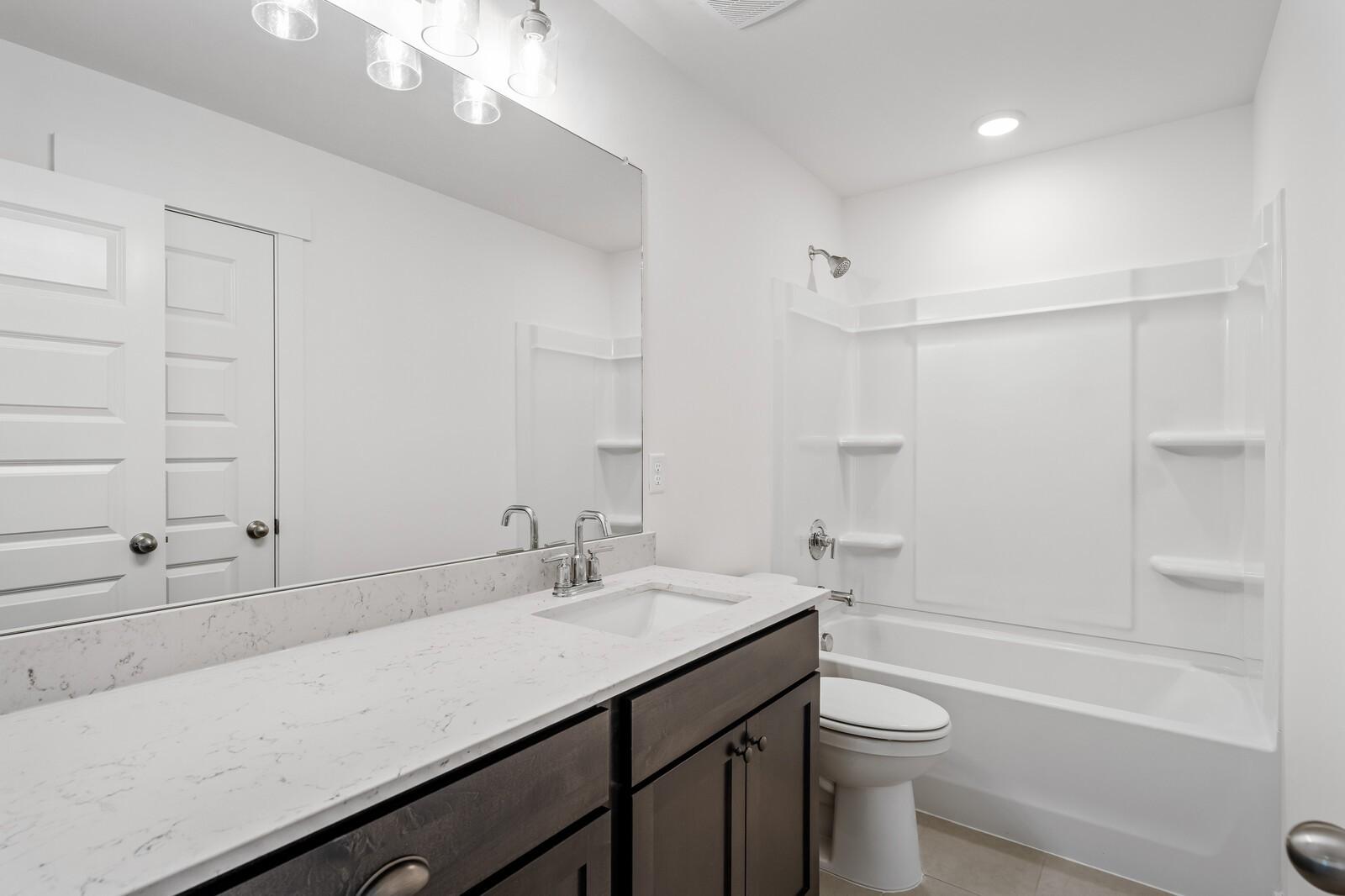 Modern bathroom with white vanity, marble-style countertop, and tub-shower combo in Woods Crossing, Gallatin, Tennessee.
