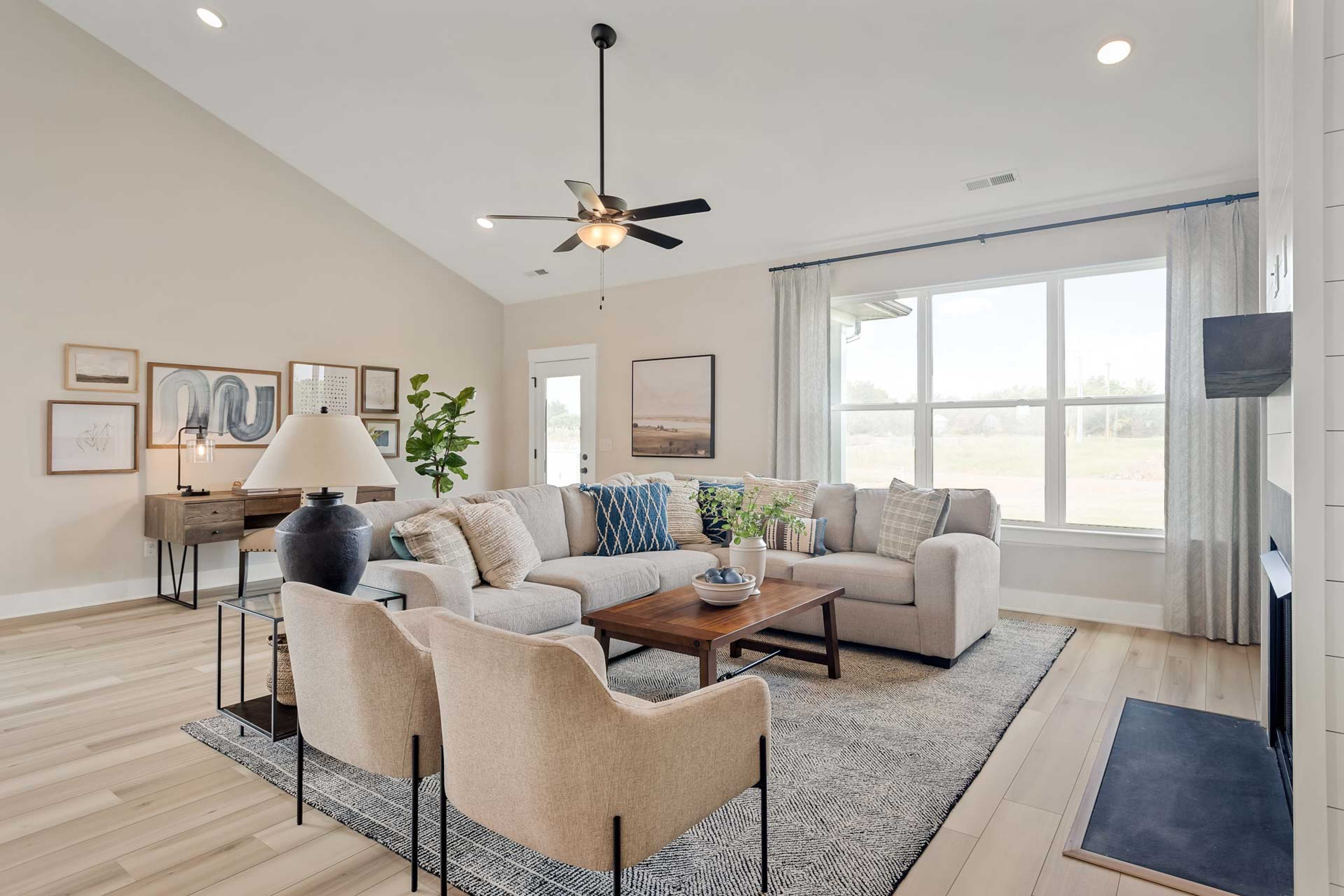 Open-concept living room at Salem Landing in Murfreesboro TN with beige sectional sofa, hardwood floors, ceiling fan, and large windows