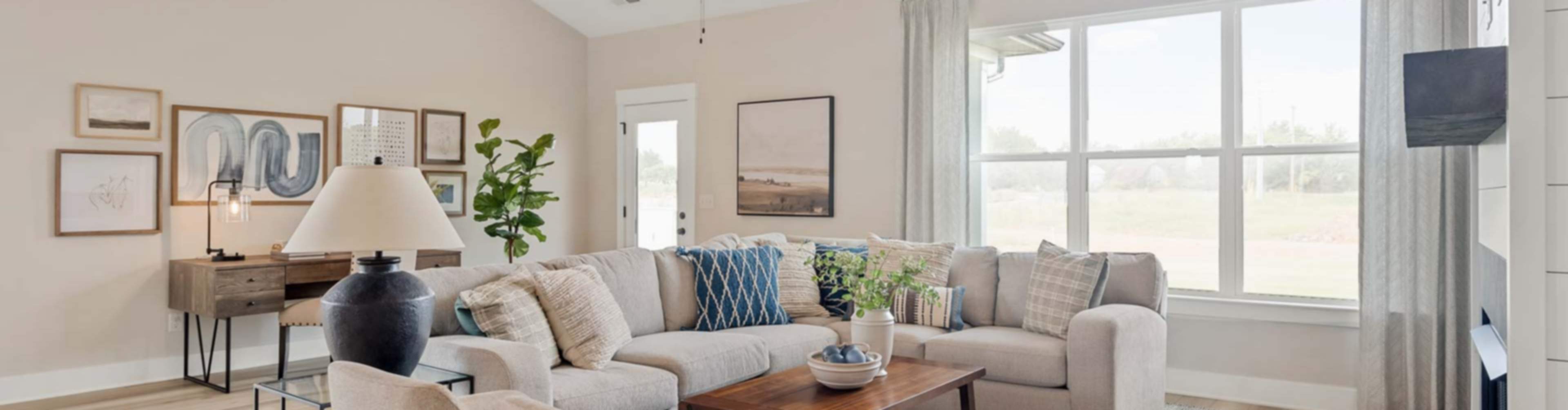 Spacious living room in new White House home featuring L-shaped sofa, fireplace, ceiling fan, and large windows