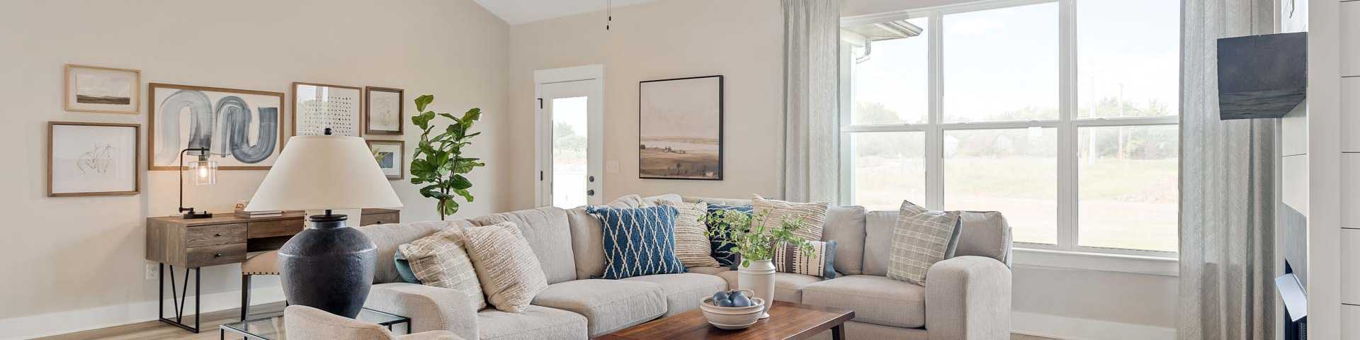 Spacious living room in new White House home featuring L-shaped sofa, fireplace, ceiling fan, and large windows