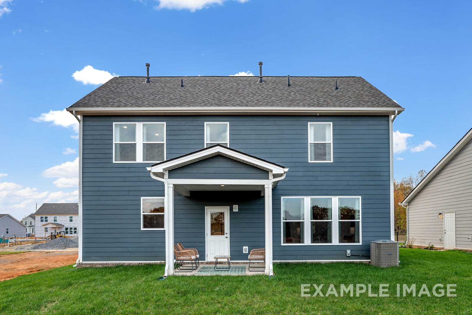 Rear elevation of The Gordon B two-story home with navy blue siding, covered porch, large windows, and grassy yard in White House, TN