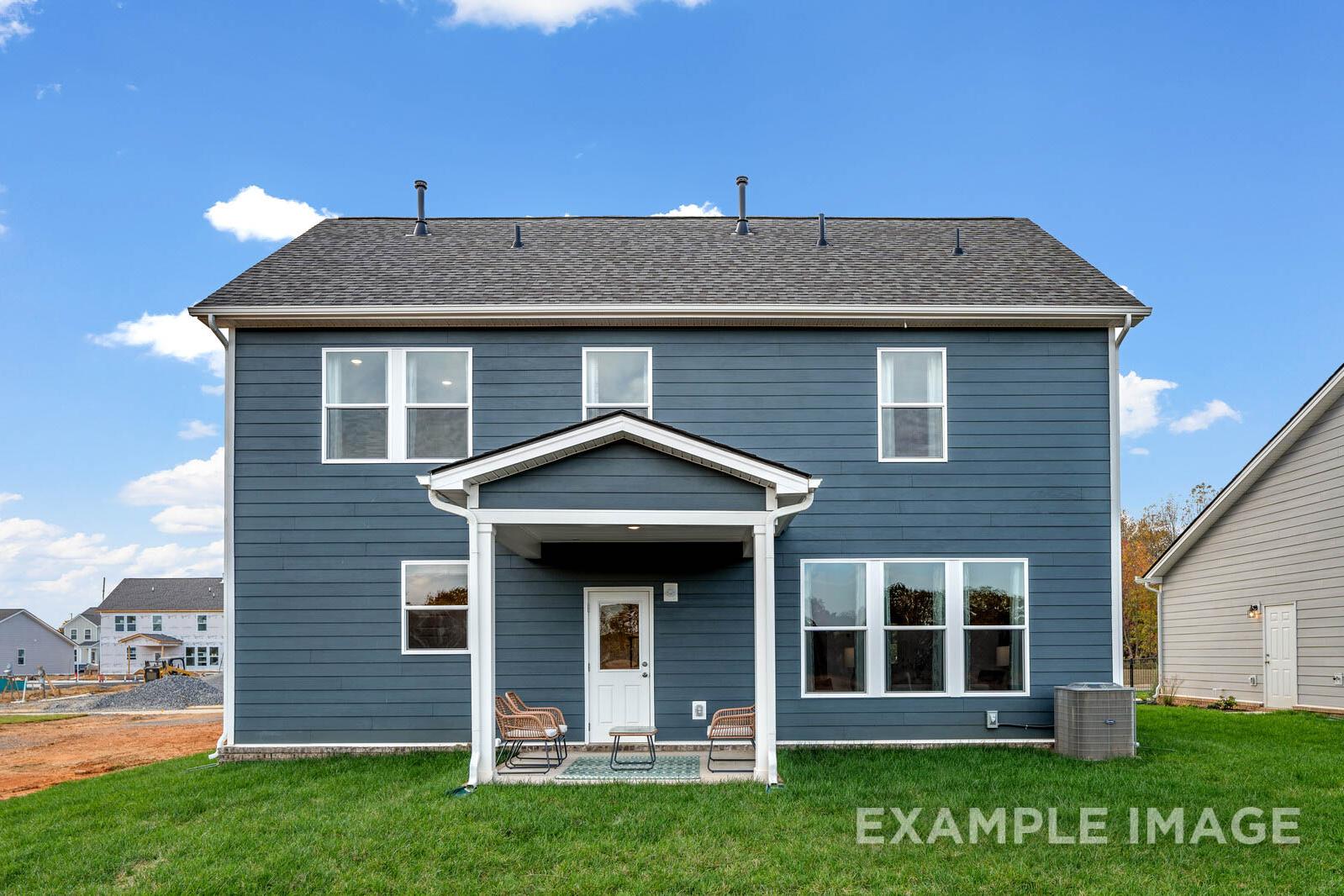 Rear elevation of The Gordon C two-story home with navy blue siding, covered porch, and grassy yard
