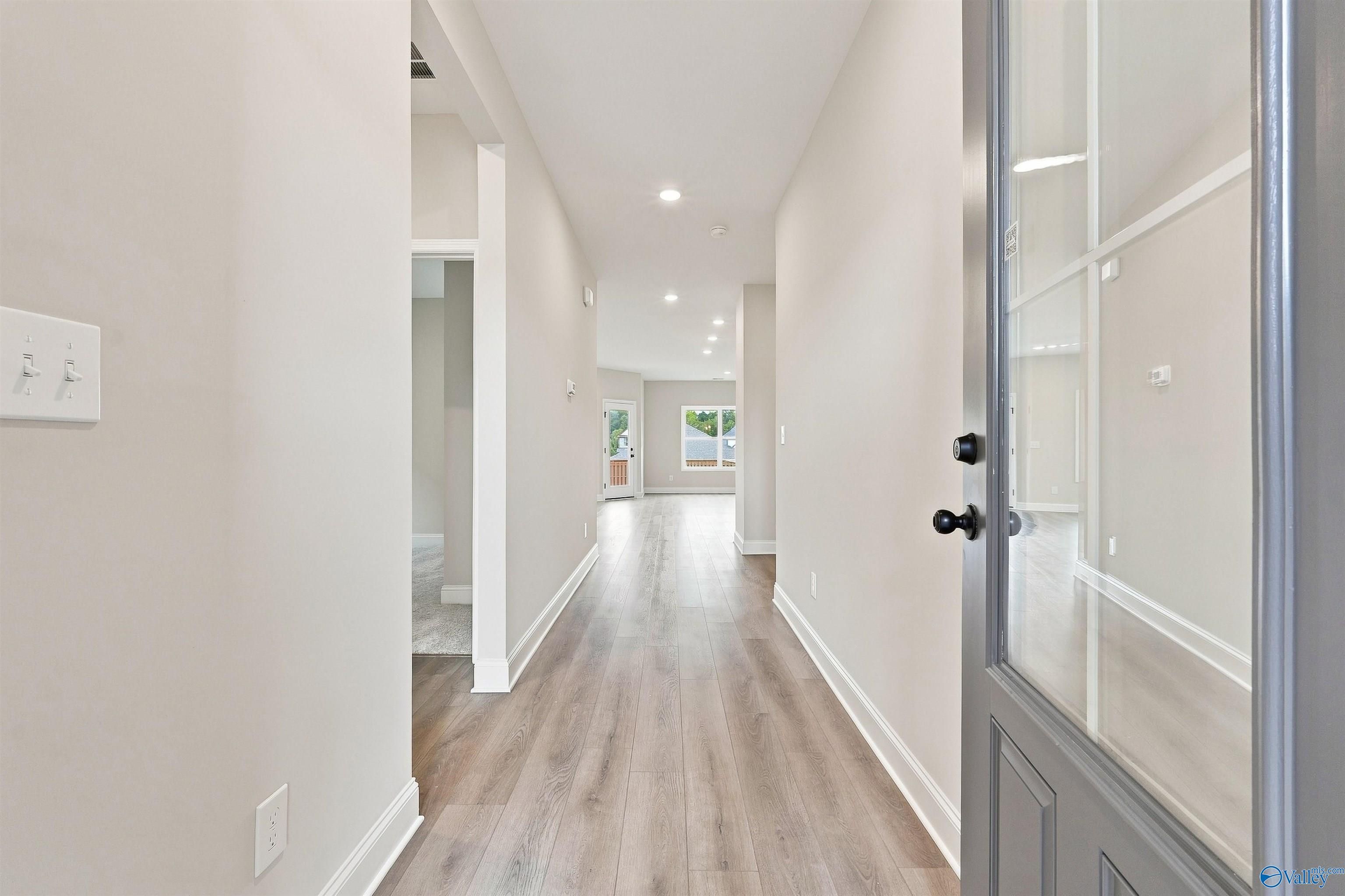 Bright entry foyer with gray glass-panel front door and luxury vinyl plank flooring in Davidson Homes The Franklin C, Athens, Alabama