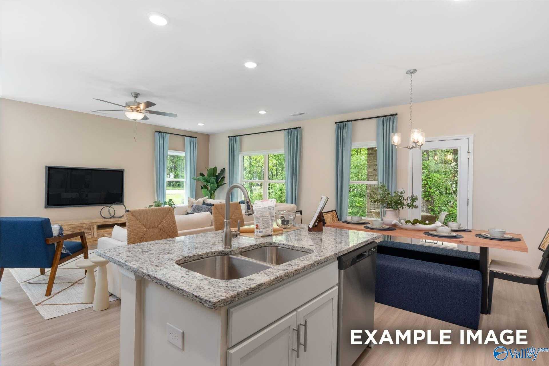 Bright open-concept kitchen with granite island, farmhouse sink, and dining area in Davidson Homes The Camden B, Huntsville, Alabama