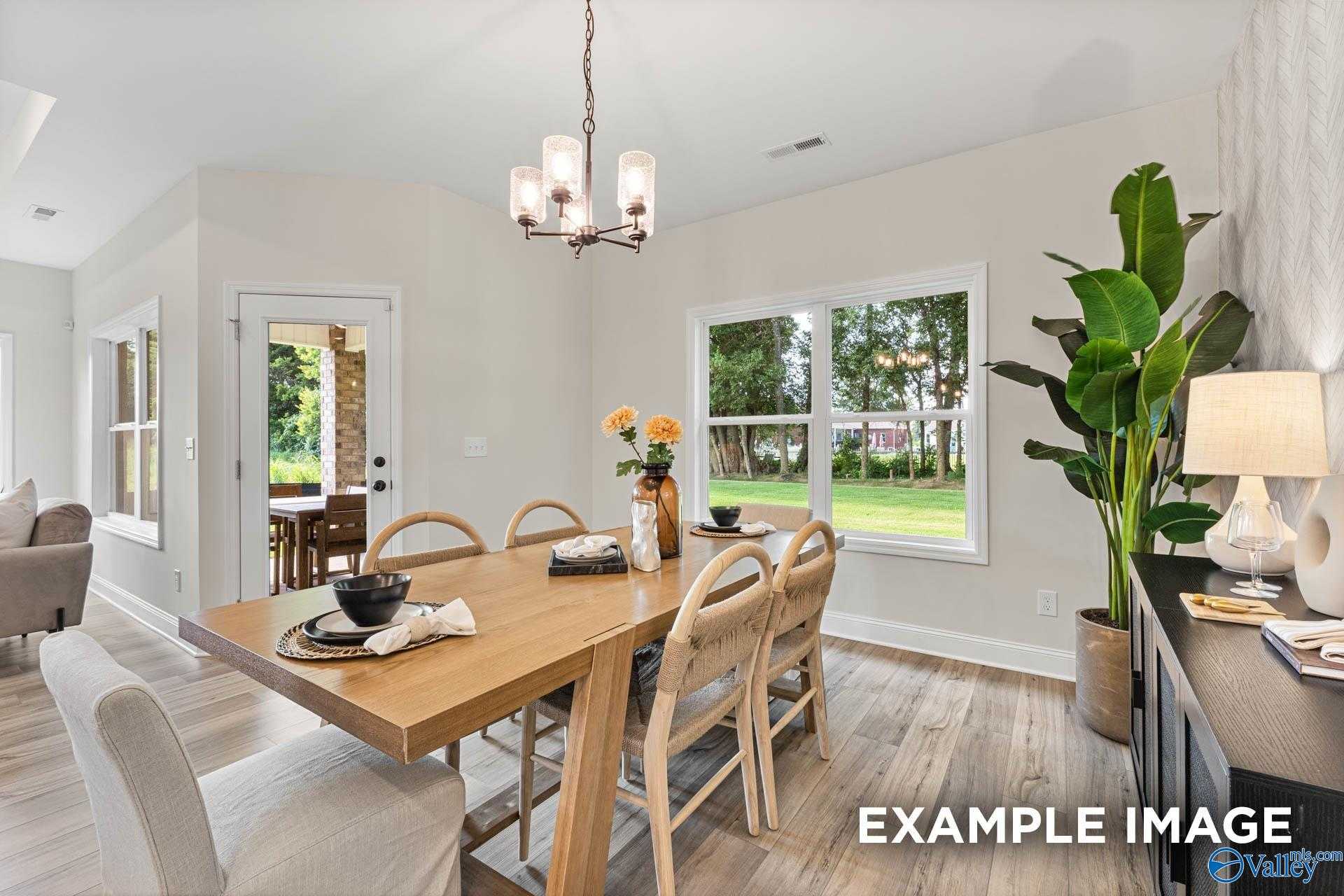Elegant dining room featuring wooden table, upholstered chairs, chandelier, and lush garden view in Davidson Homes The Franklin, Huntsville AL