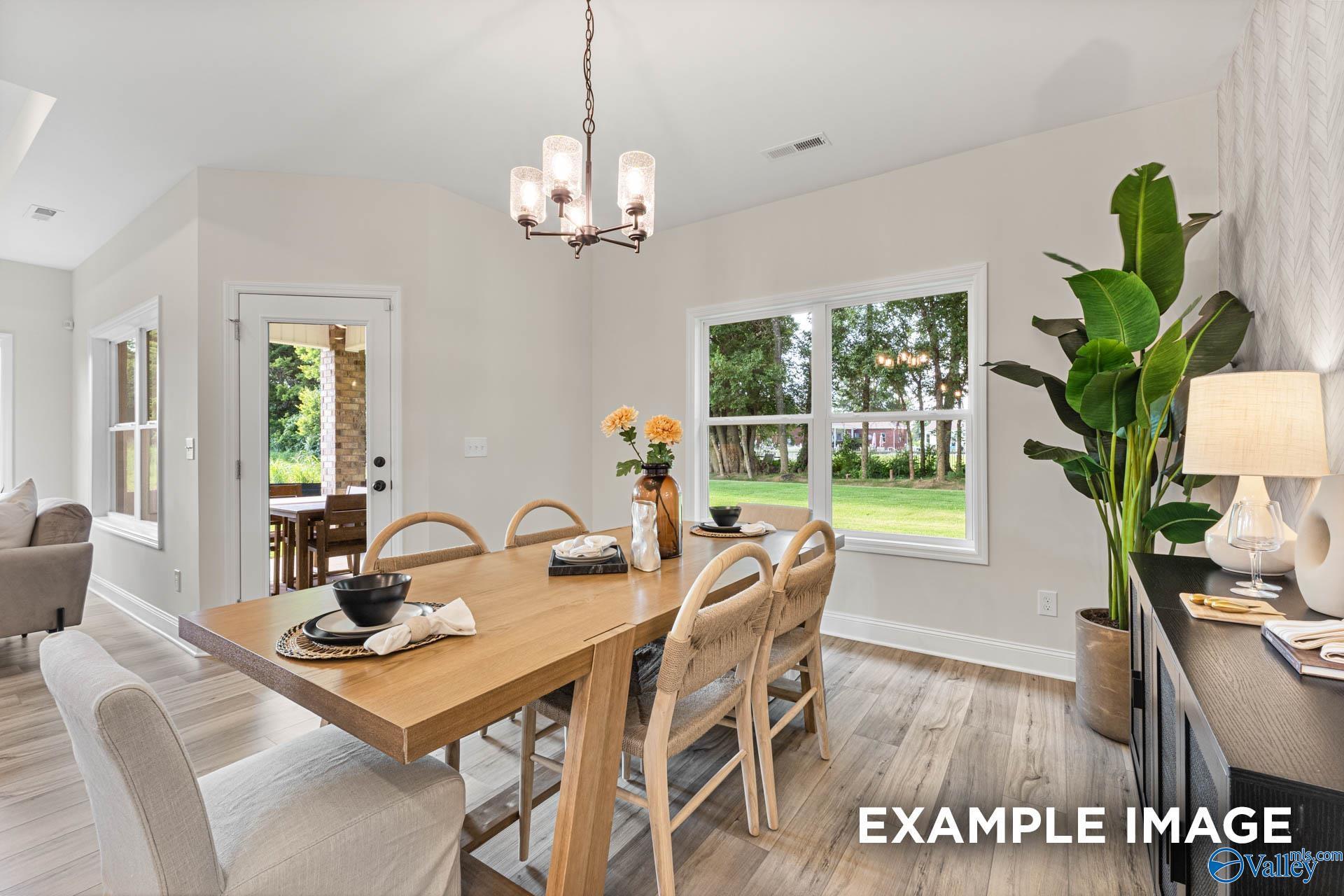 Elegant dining room with wooden table, upholstered chairs, chandelier, and garden-view windows in The Franklin home, Huntsville, AL