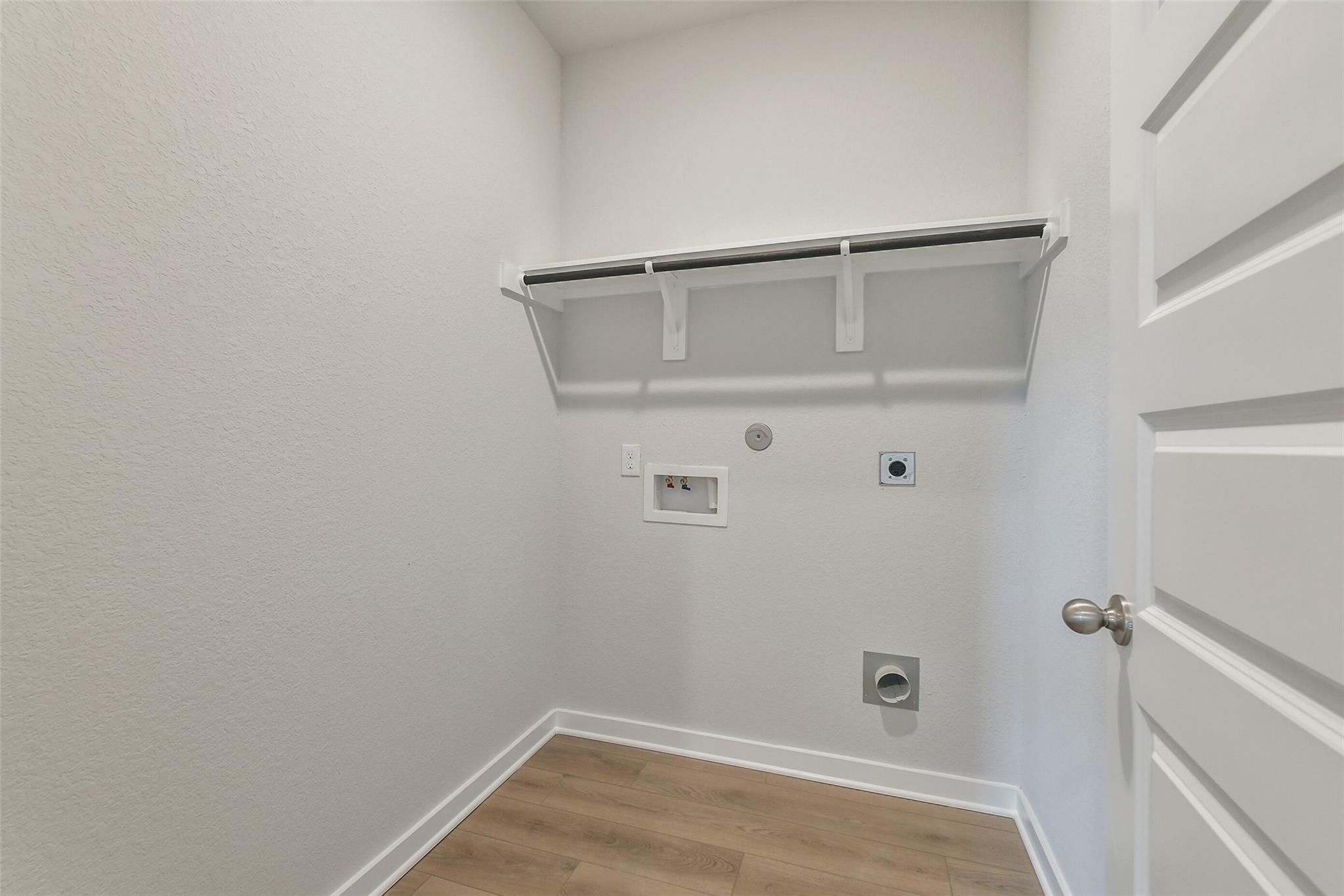 Spacious laundry room with built-in upper shelving, washer/dryer hookups in Davidson Homes The Brazos E, Liberty Estates, Cleveland, Texas