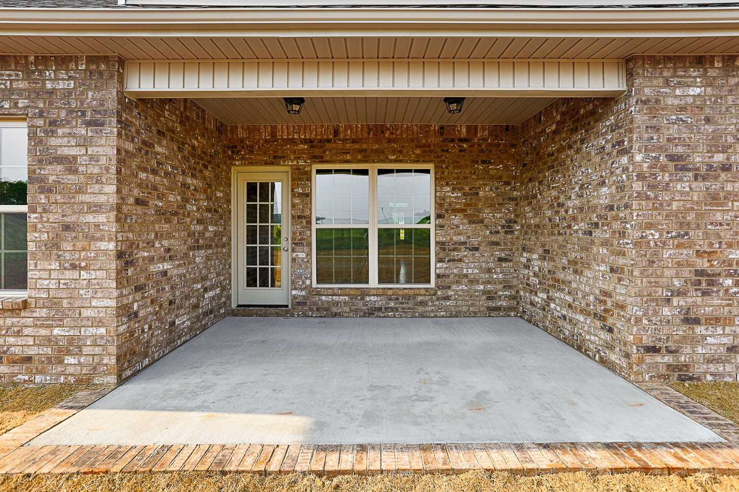 Covered patio of The Montgomery Davidson Homes design with brick exterior, French doors, windows, and concrete slab in Meridianville AL