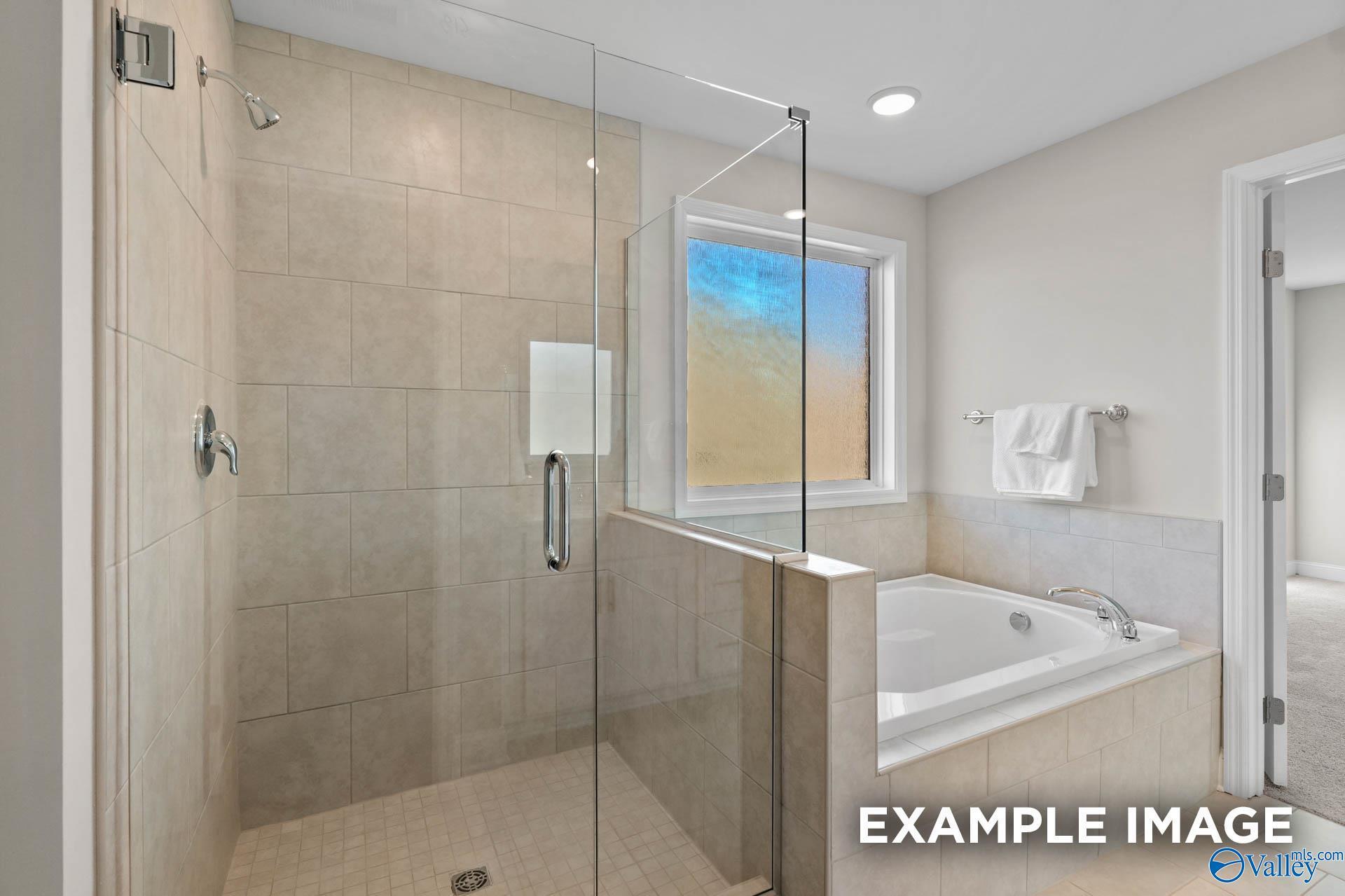 Modern master bathroom with glass-enclosed walk-in shower and soaking tub in The Meadows, Athens home by Davidson Homes.